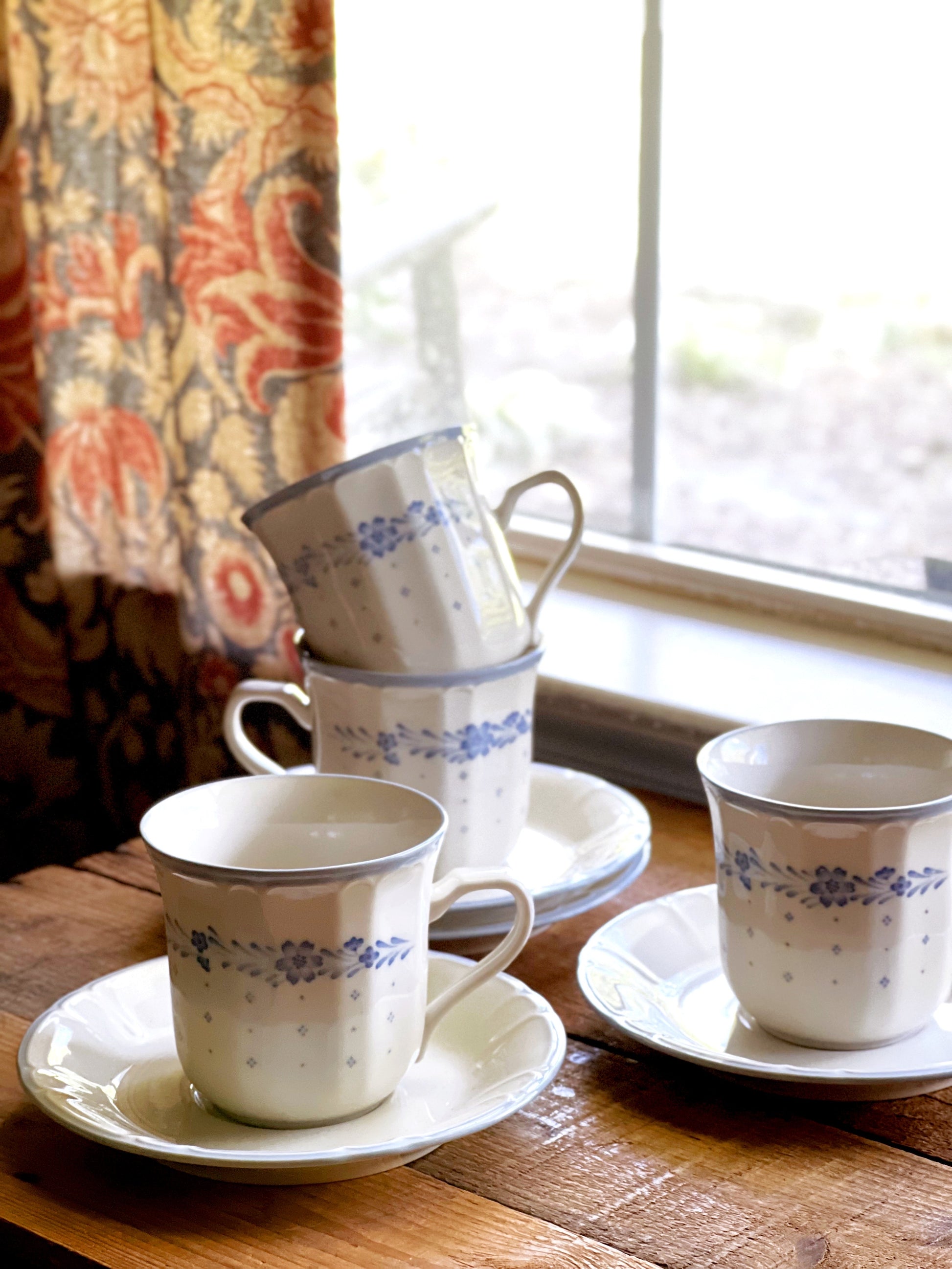 Sango Arcadia Blue teacups and saucers on a rustic wood table