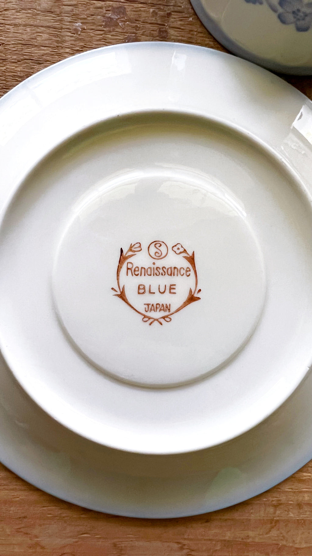 White ceramic plate with 'Renaissance Blue Japan' branding on a wooden surface