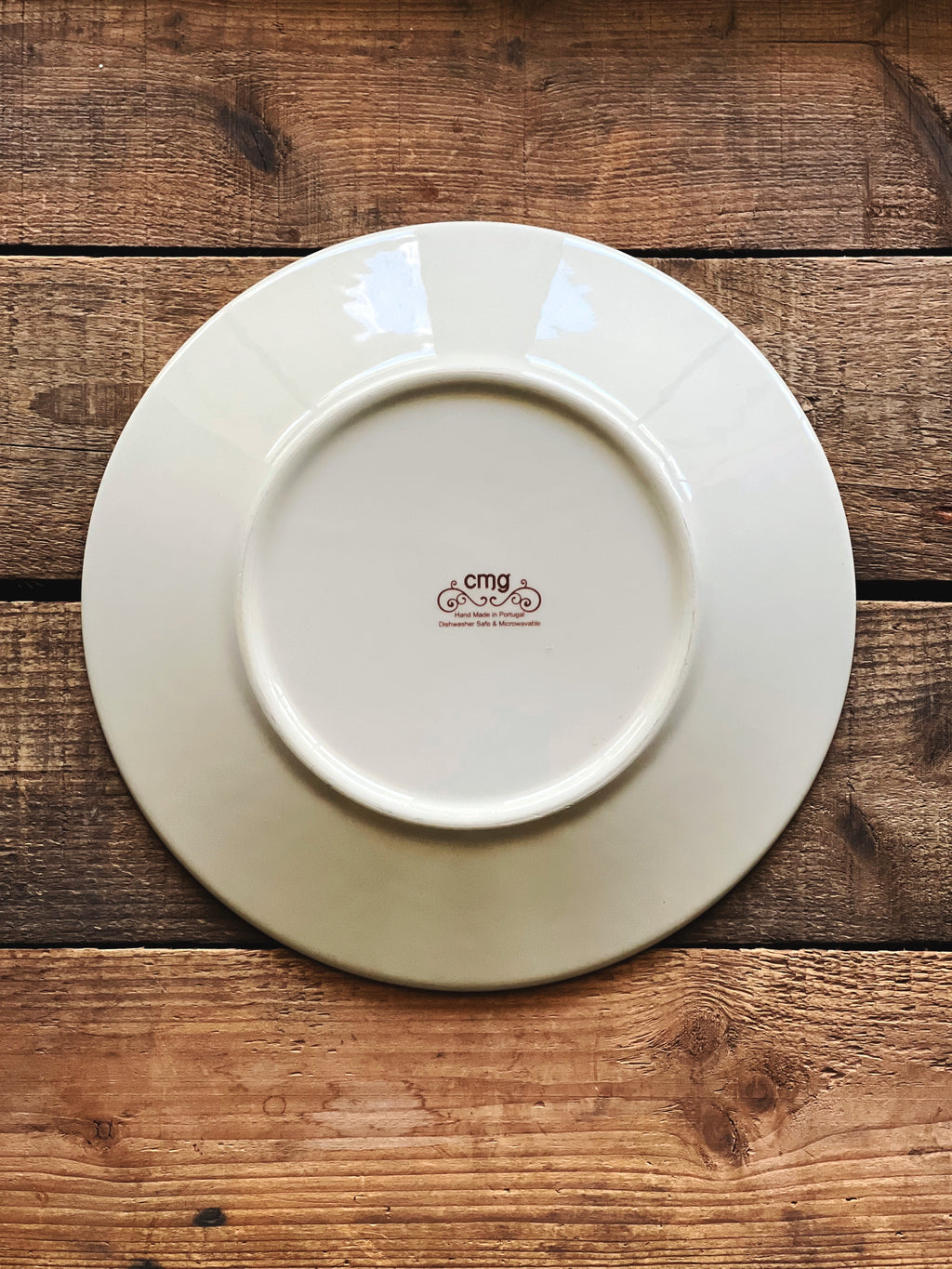 Underside of a CMG Portugal ceramic luncheon plate featuring a Mediterranean-inspired floral motif and terracotta border.