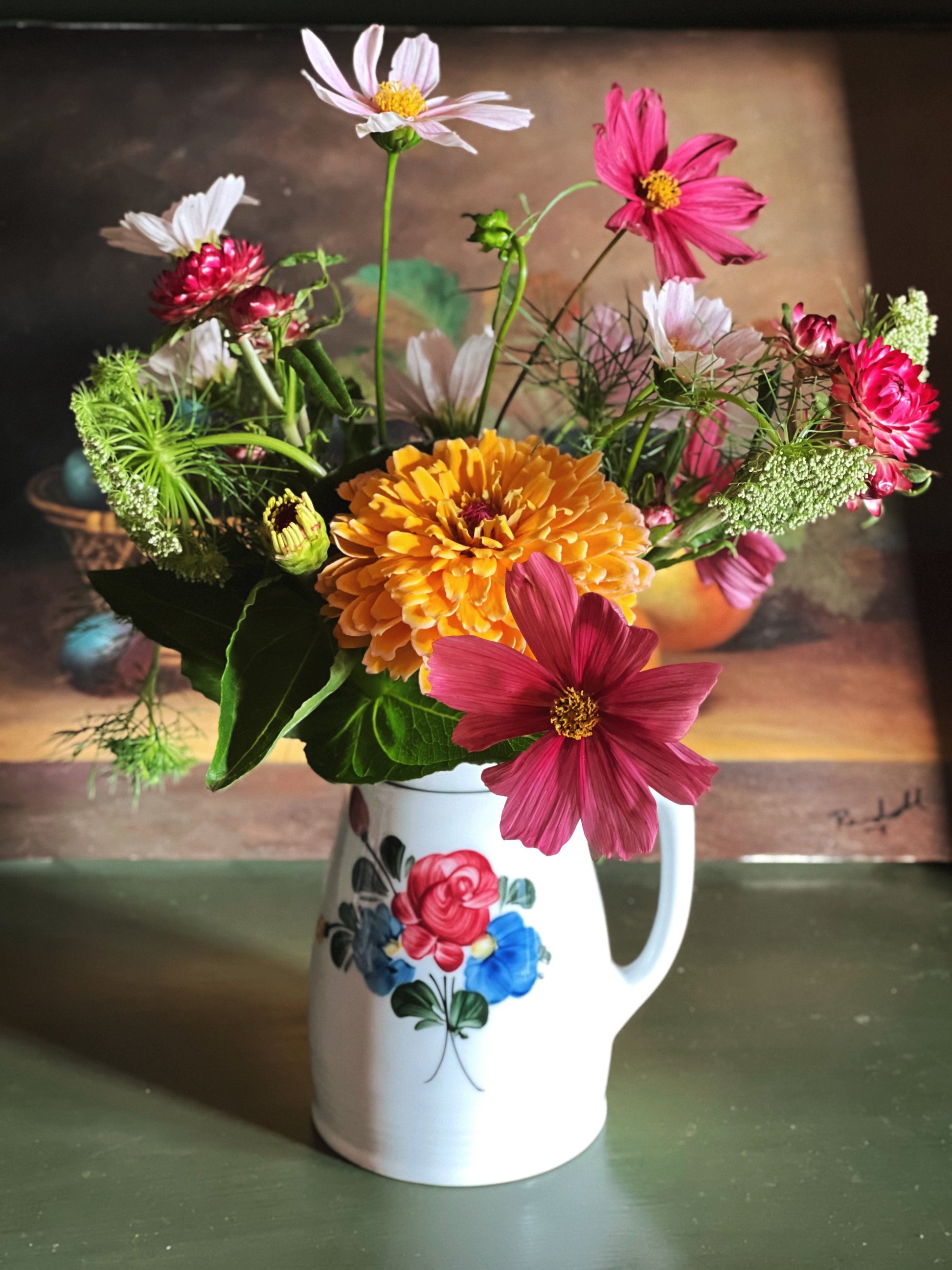 Colorful bouquet of flowers in a Vintage Lilien Porzellan Austria Floral Pitcher on a green surface.