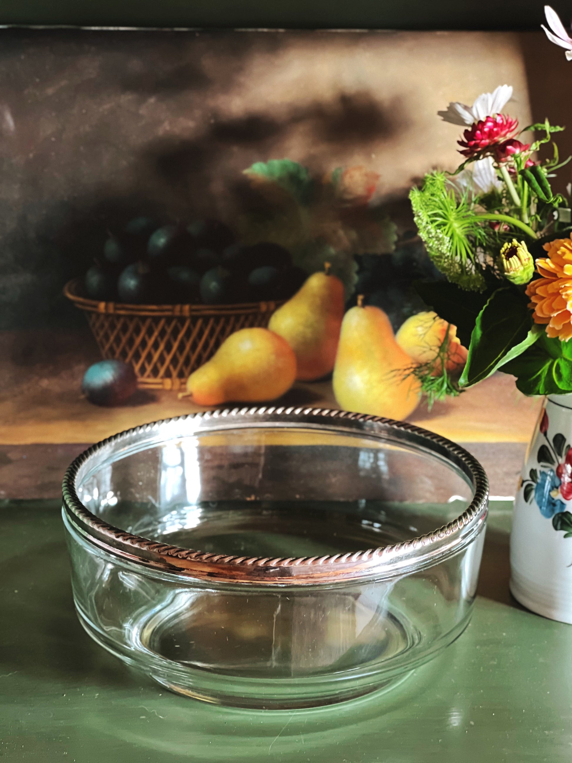 Vintage glass serving bowl with an elegant silver rope rim by a still life painting