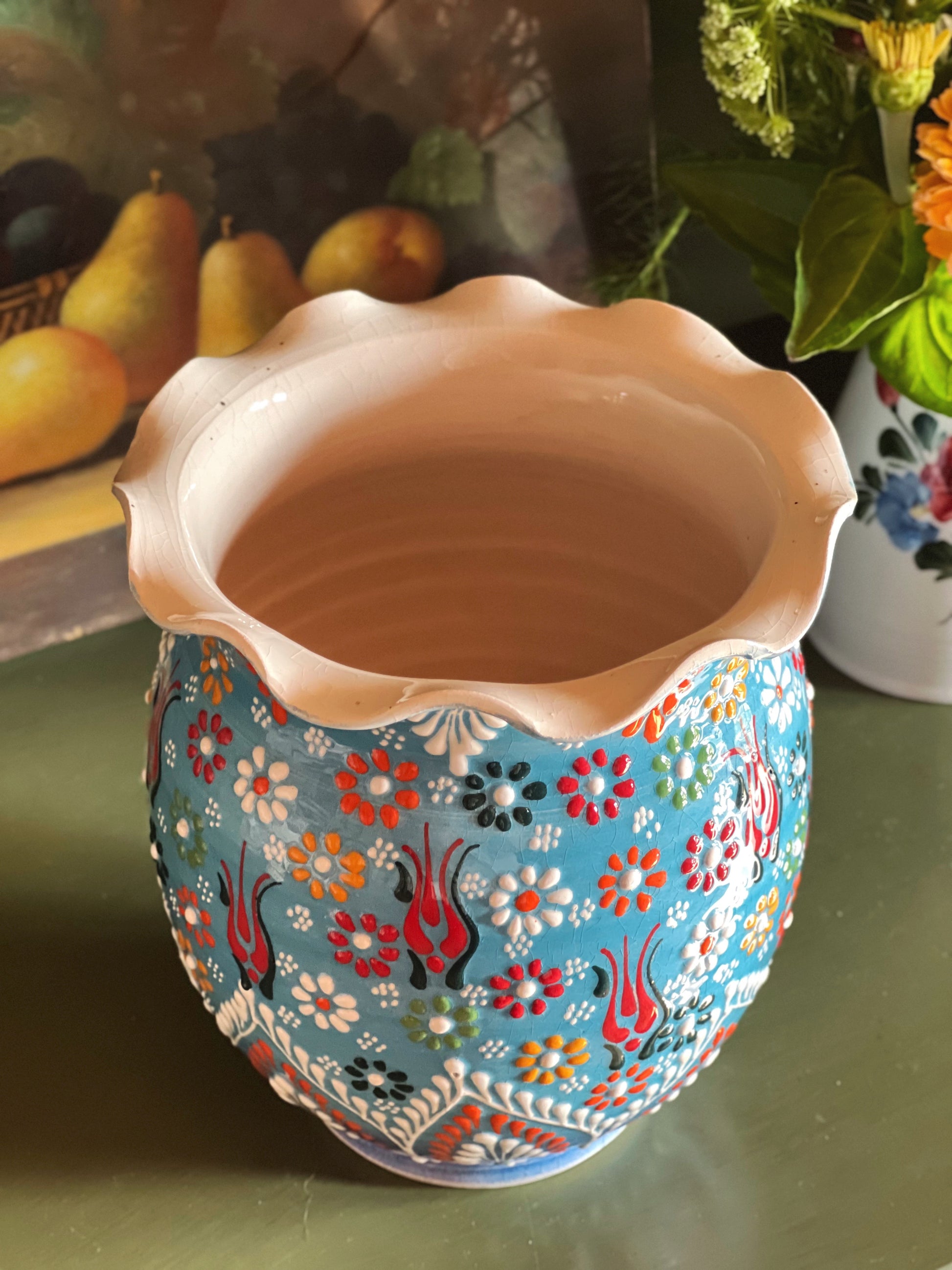 Overhead view of a vintage hand-painted ceramic vase with raised floral decoration and scalloped rim.