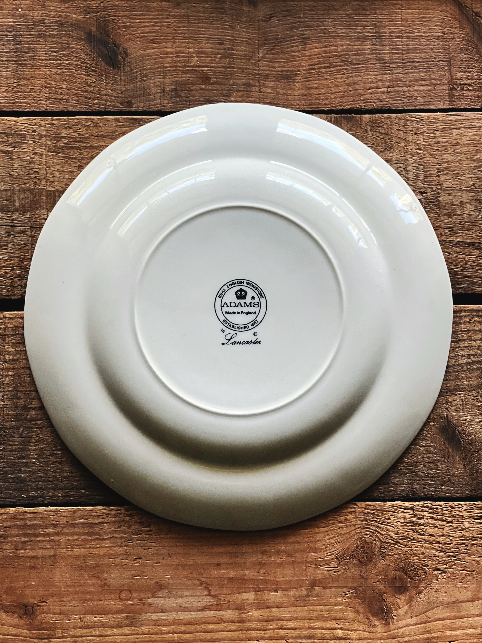 Underside of a vintage Adams Lancaster 9-inch hand-painted English luncheon plate on a rustic wooden tabletop.