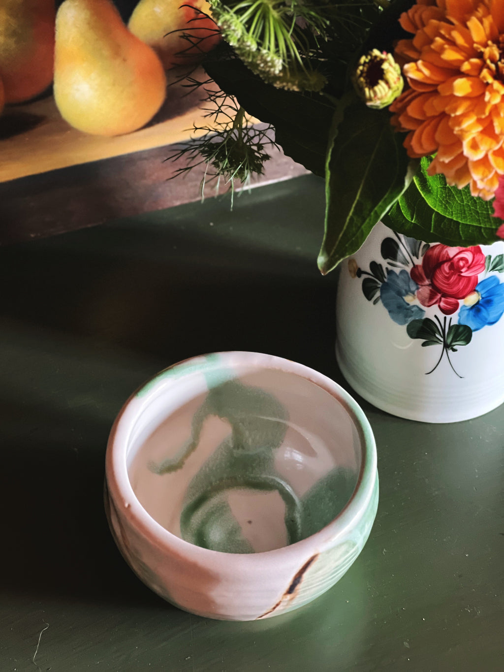 Overhead view of a Handmade signed JMC pottery bowl with a soft sage green glaze and earthy accents
