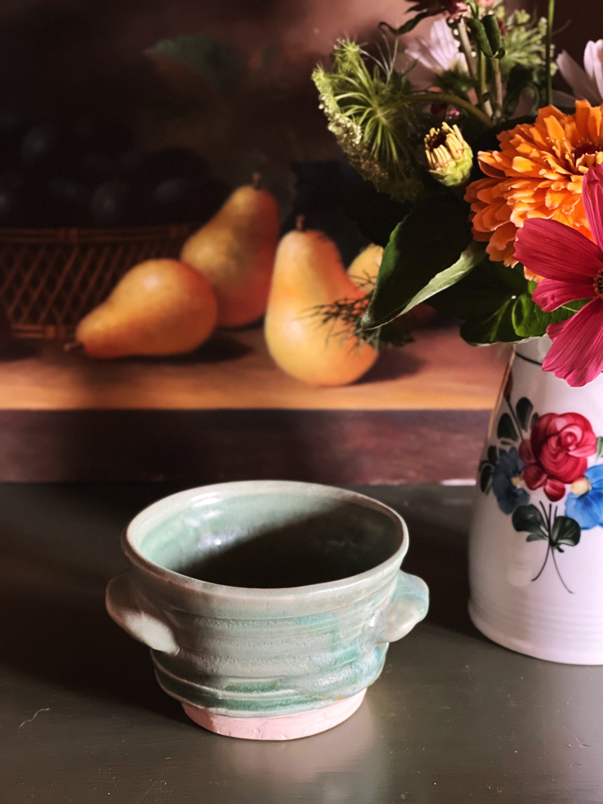 Handmade Green Handled Pottery Bowl next to a flower arrangement 