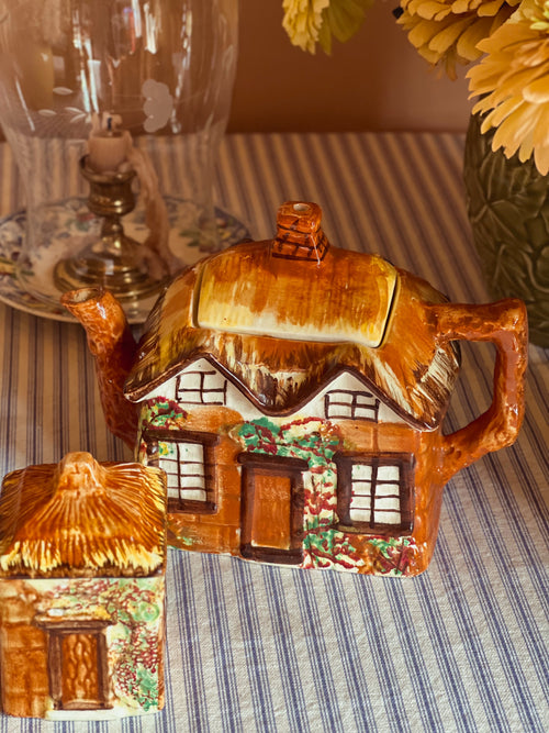 Large vintage Price Bros Ye Olde Cottage teapot made in England featuring a hand-painted storybook cottage with thatched roof, styled with fresh flowers in warm natural light.