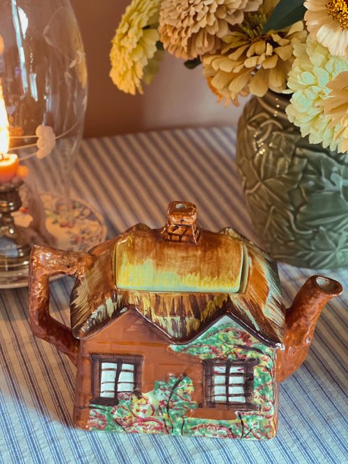 backside of a Large vintage Price Bros Ye Olde Cottage teapot made in England featuring a hand-painted storybook cottage with thatched roof, styled with fresh flowers in warm natural light.