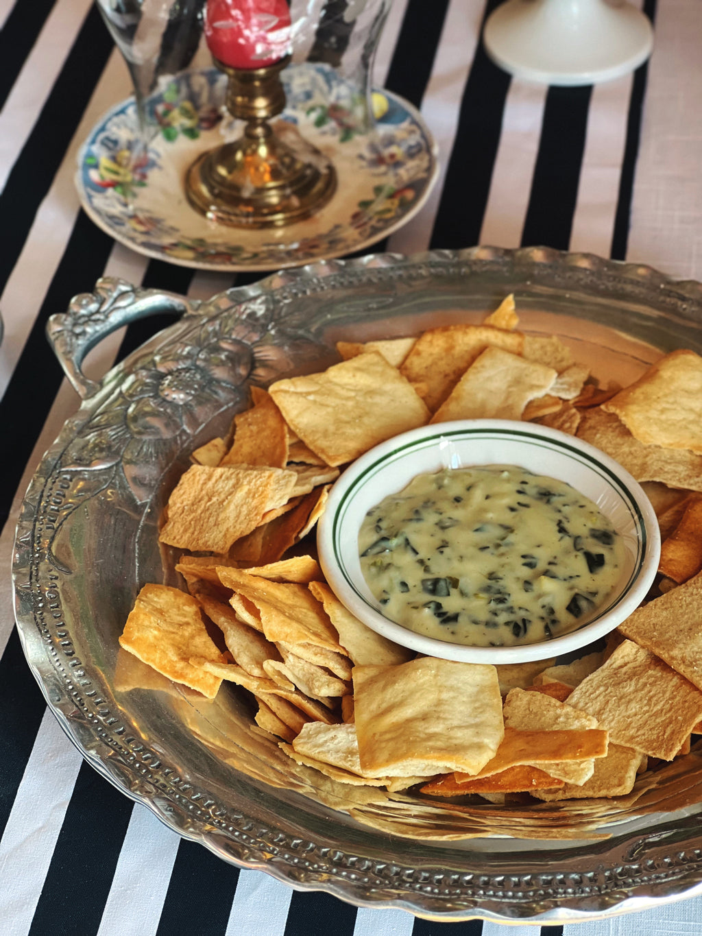 Vintage embossed silver serving tray with decorative fruit border and double handles with pita chips and spinach dip. 