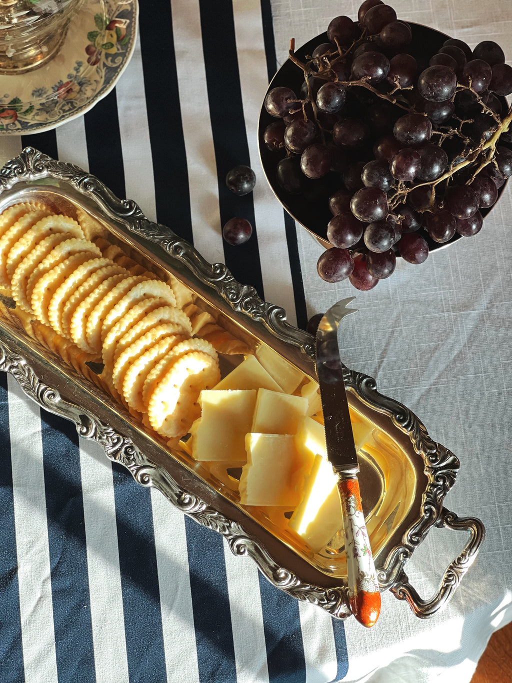 Vintage Ornate Footed Silver Serving Tray with cheese and crackers on a table set with grapes