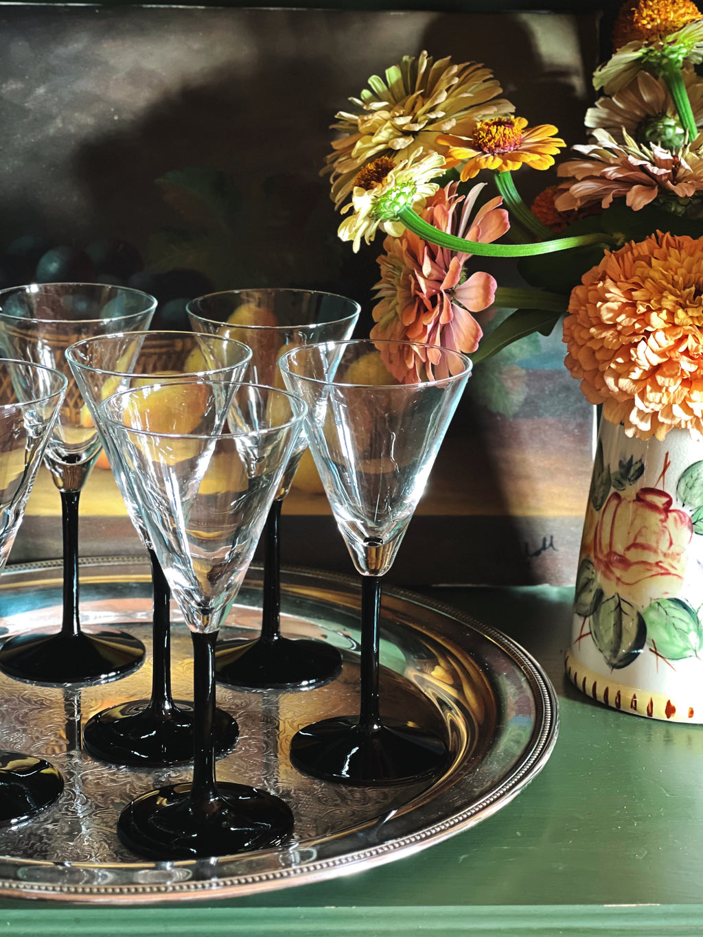 Vintage Crystal Martini Glasses with Black Stems on a silver tray next to a jug of flowers 