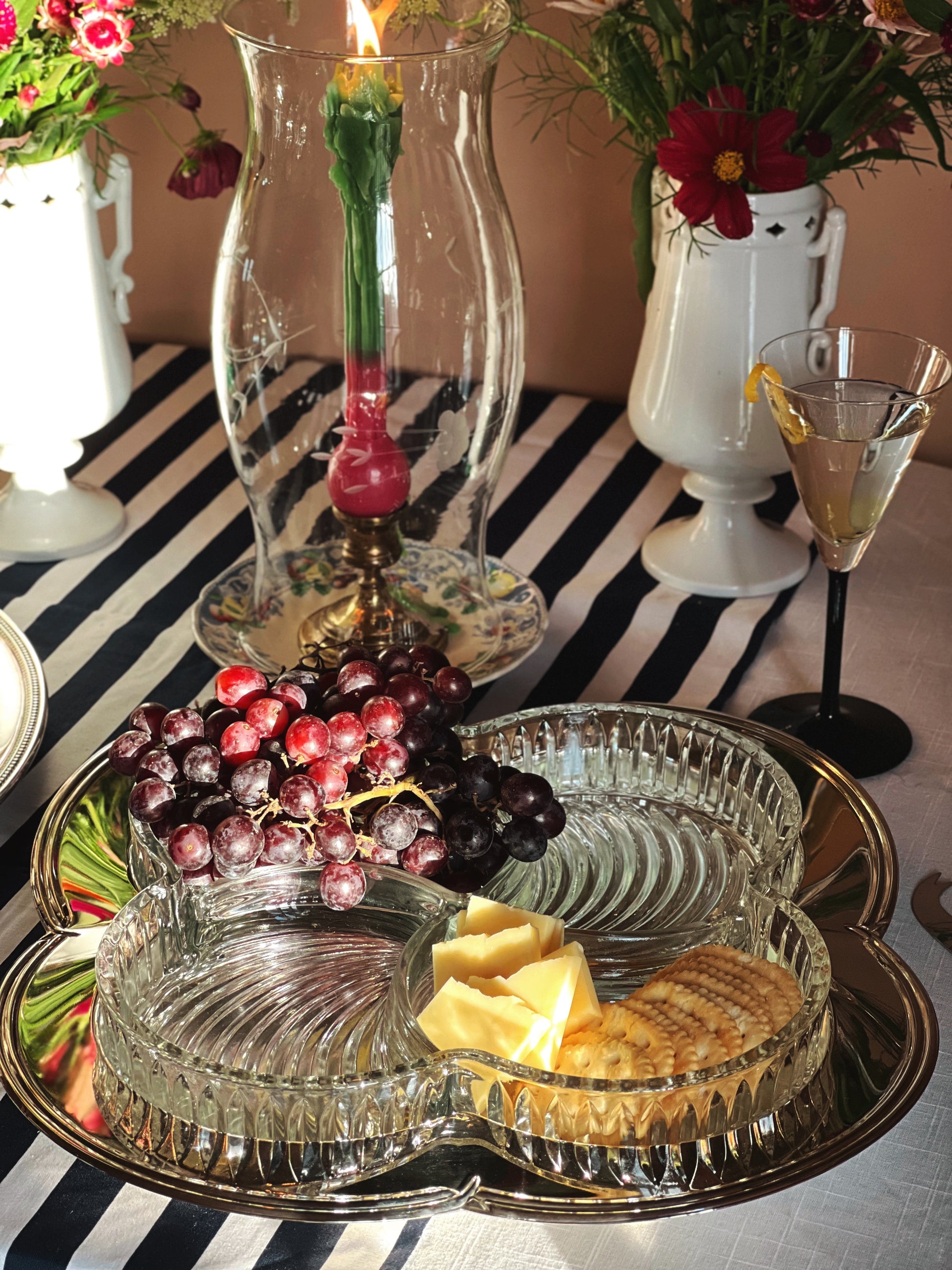 Vintage Godinger Contour Silver Plate Relish Tray with Removable Cut Glass Insert styled on a table with a martini glass, flowers, candlelight and a striped tablecloth