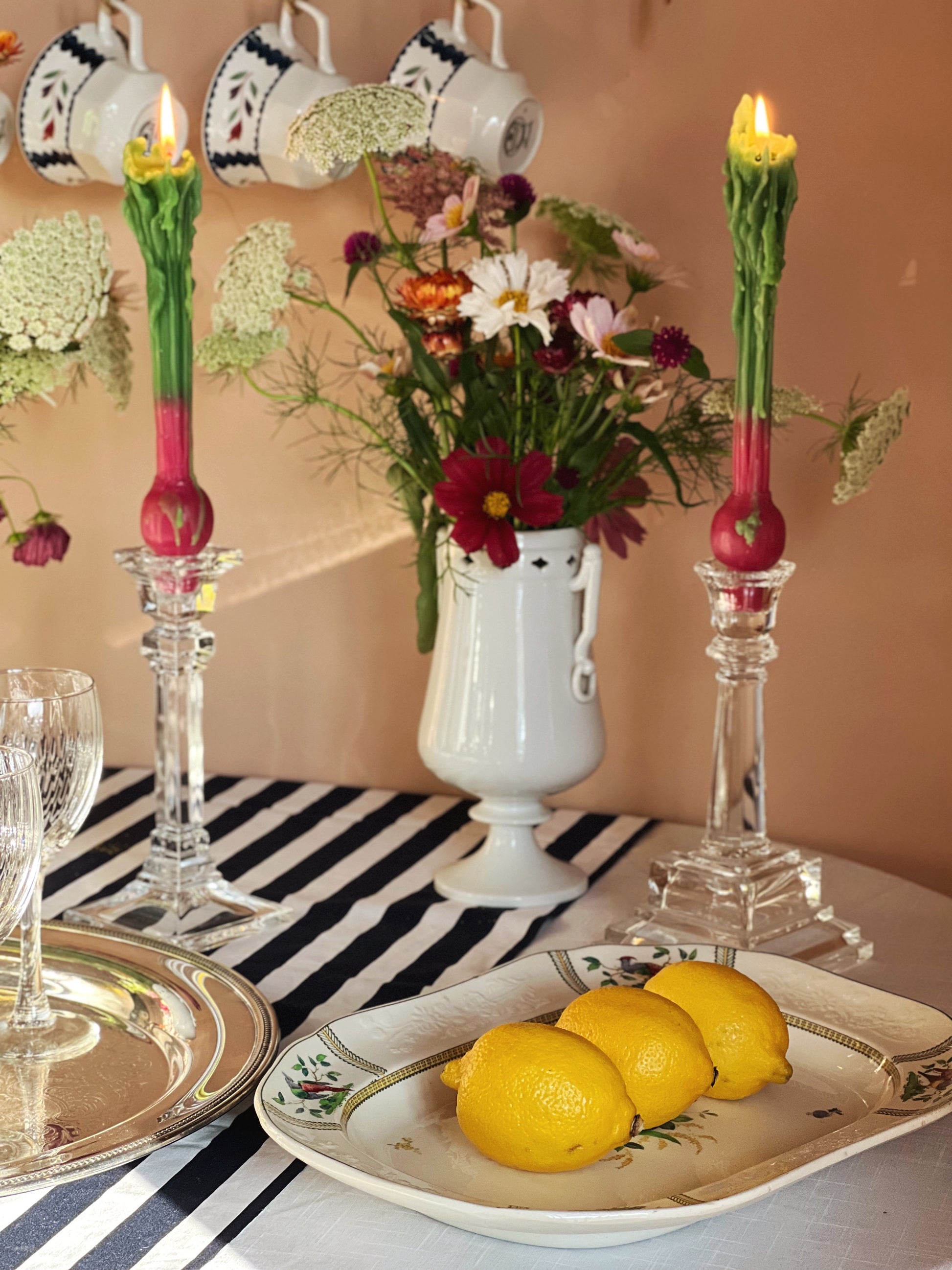 table set with glass candlesticks, fresh flowers and a platter with lemons