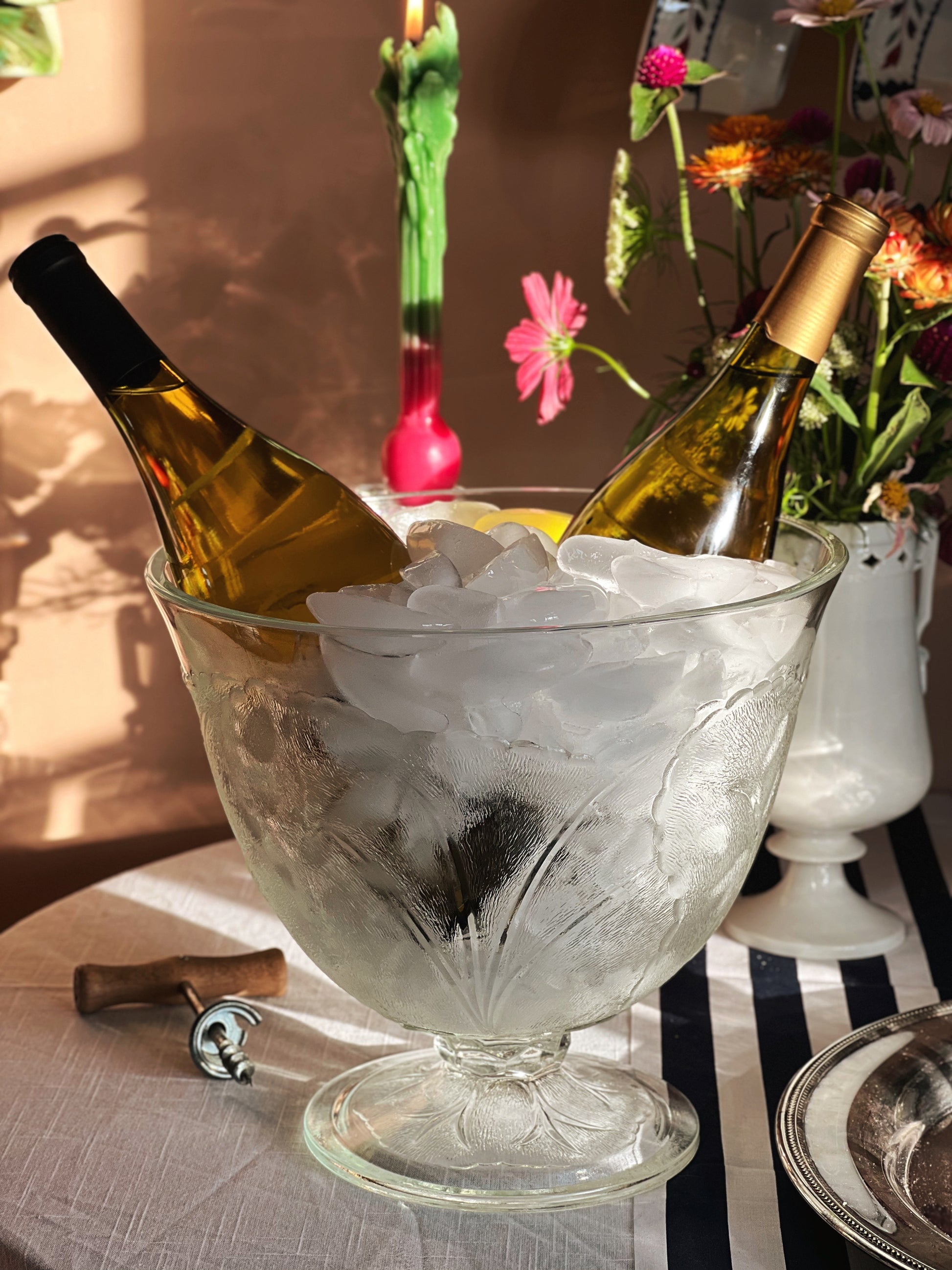 Vintage Glass Cabbage Leaf Pedestal Bowl filled with ice and wine bottles on a table set for entertaining