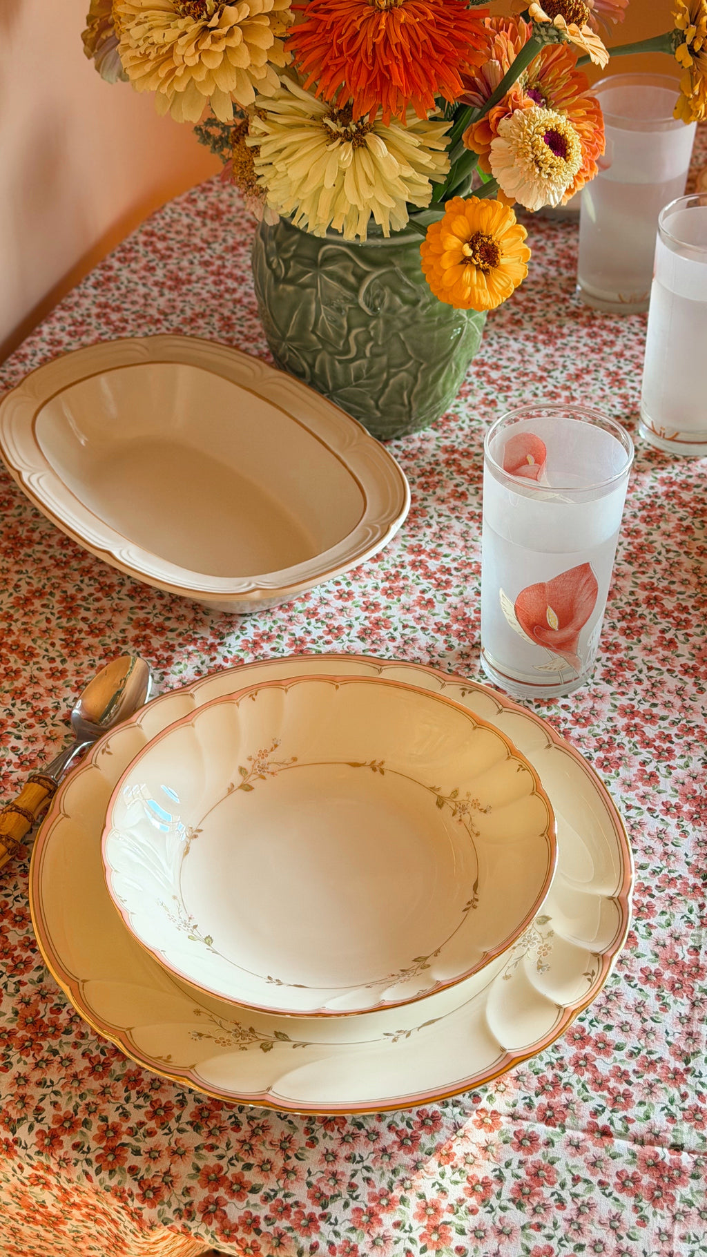 Vintage Mikasa Monticello coupe soup bowl made in Japan with a delicate pink floral border and gold trim set on a table with frosted glassware, a floral tablecloth and fresh flowers