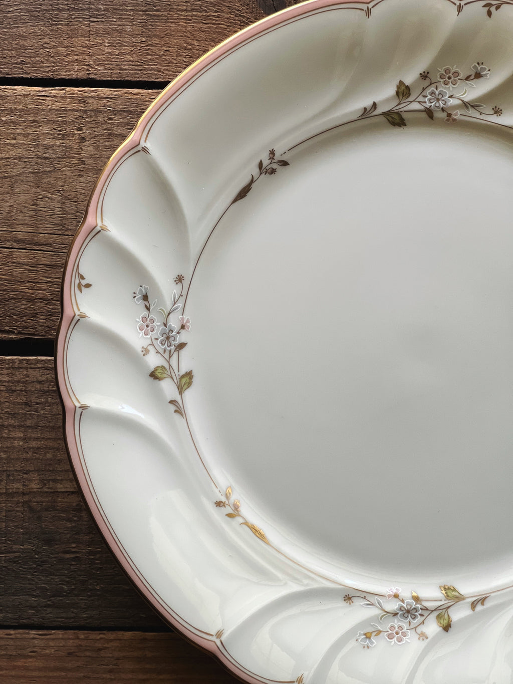 Close up of a vintage Mikasa Monticello dinner plate made in Japan with a delicate blush floral border and gold trim. 