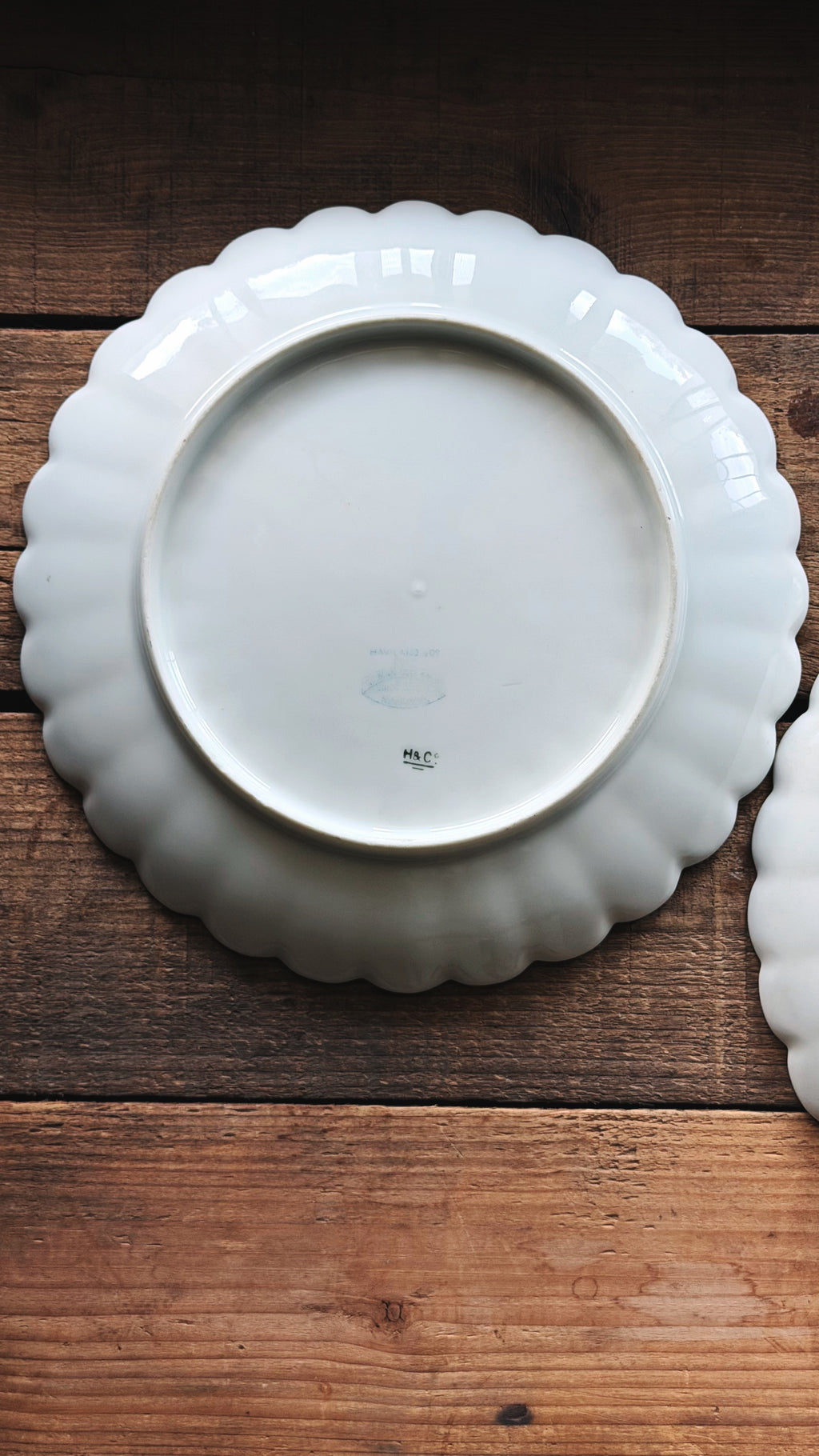A white ceramic plate with a scalloped rim, photographed from above on a rustic wooden surface.