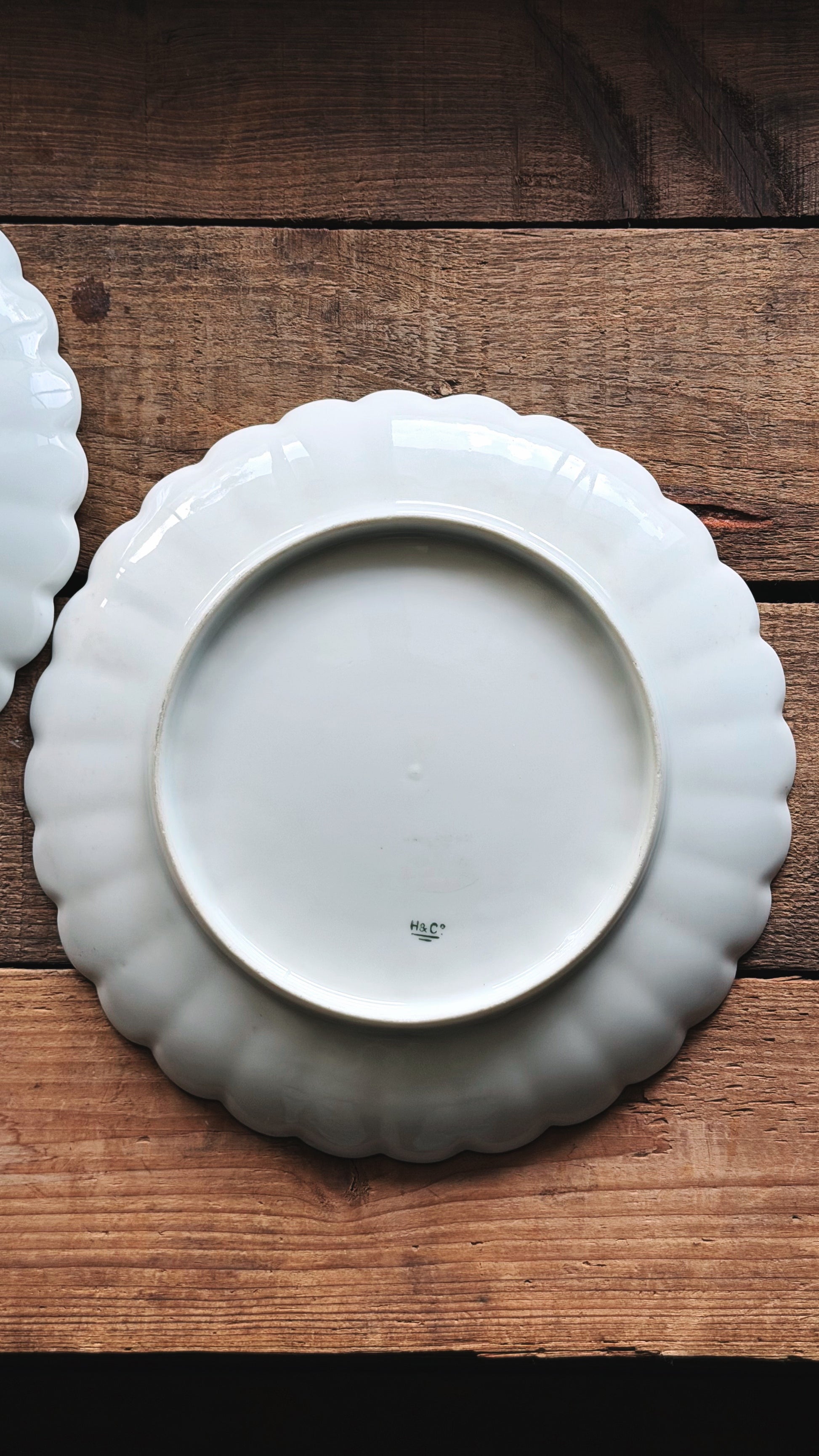A white ceramic plate with a scalloped rim, photographed from above on a rustic wooden surface.