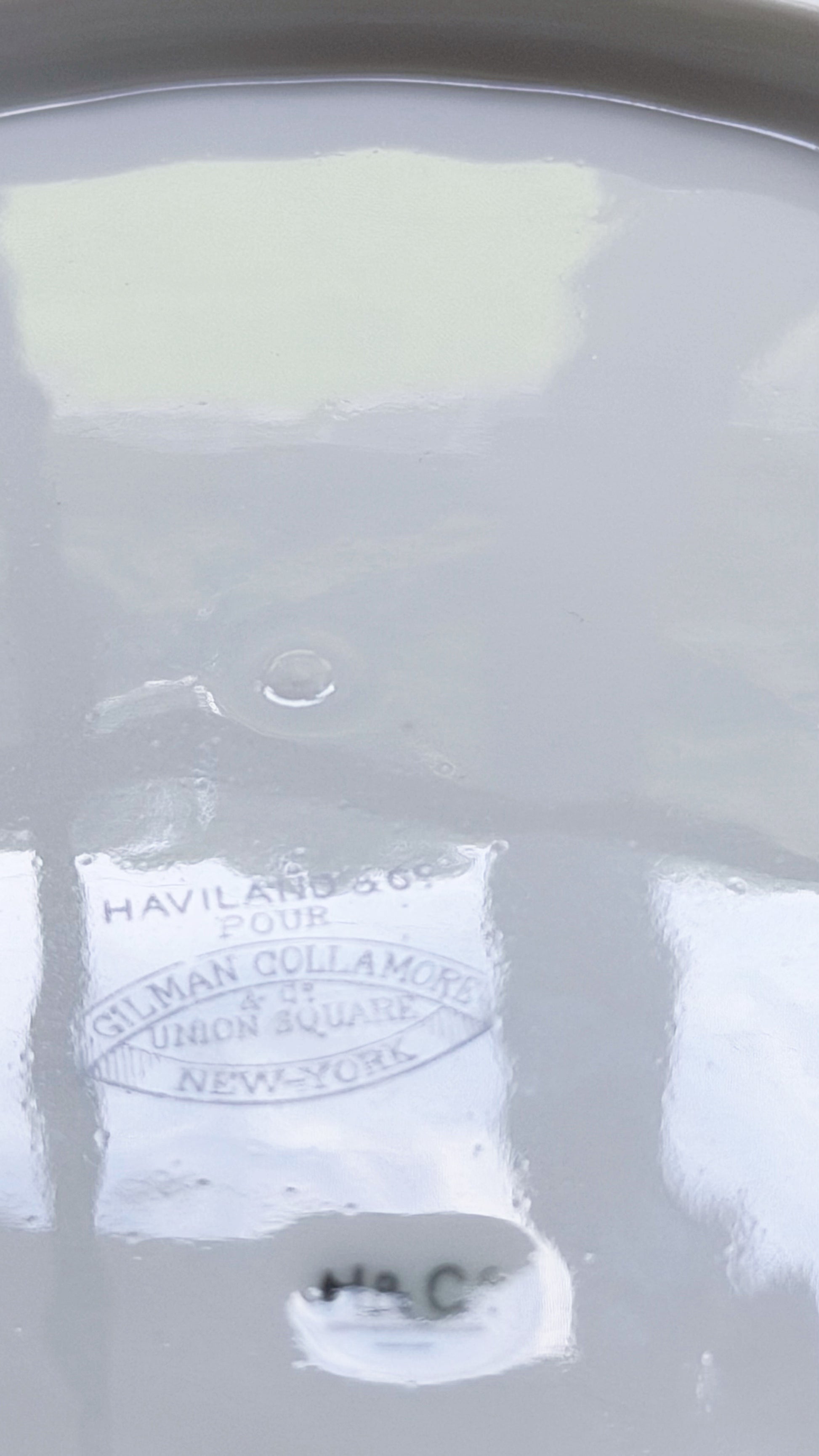 Close-up of the  bottom of a white porcelain Limoges salad plate with Gilman Collamore Union Square New York branding
