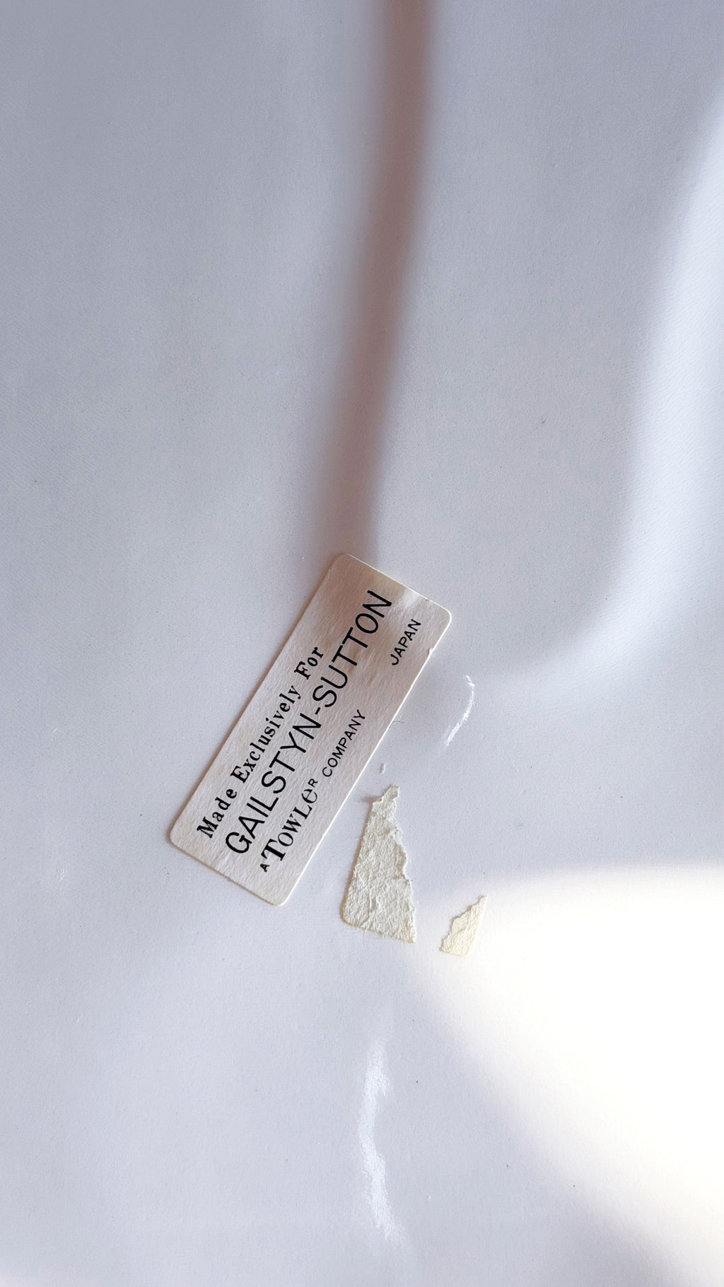 A small rectangular cream-colored label with black text reading 'Made Exclusively For' and 'GALSTYN-SUTTON' lies on a white surface 