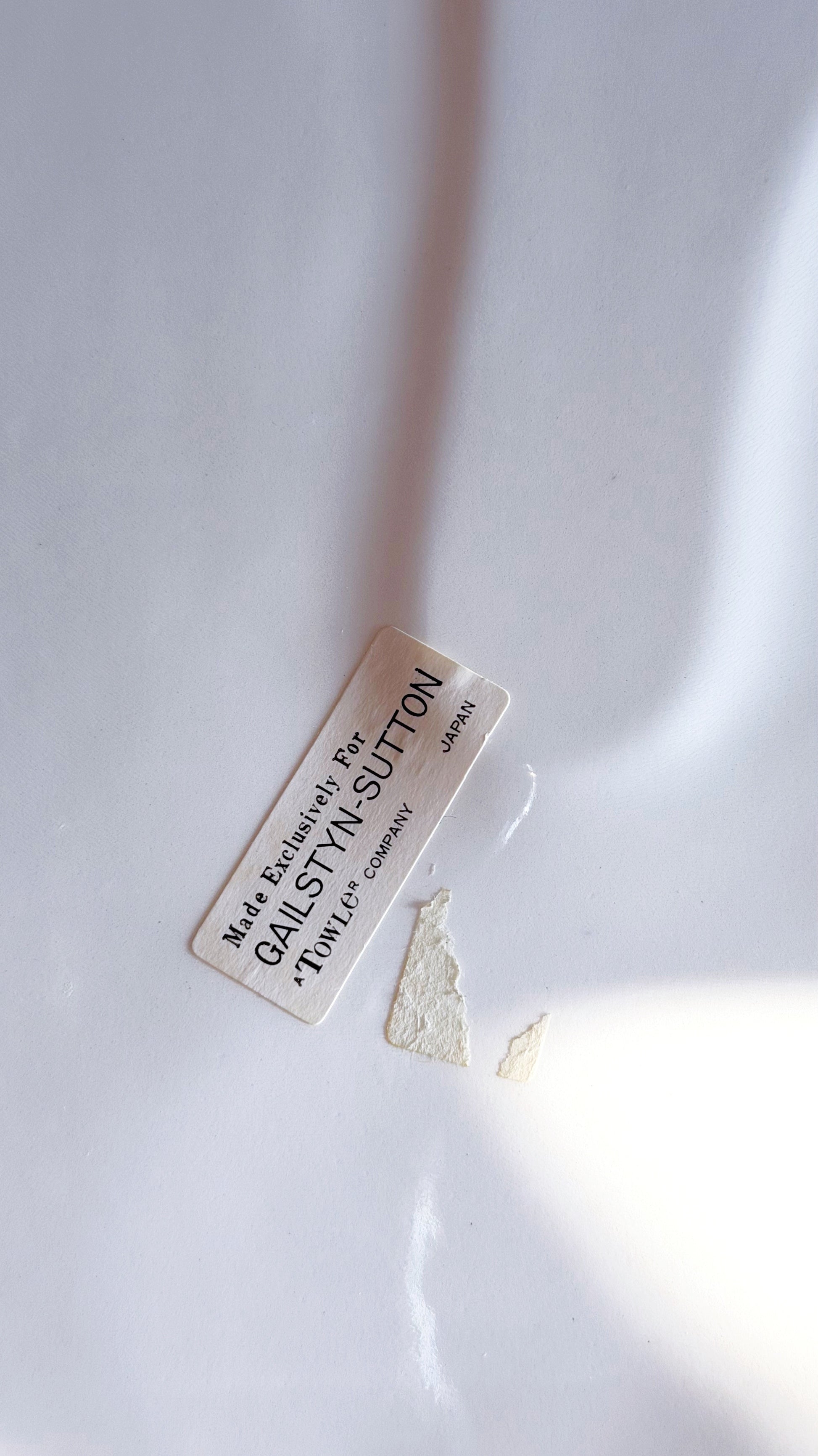 A small rectangular cream-colored label with black text reading 'Made Exclusively For' and 'GALSTYN-SUTTON' lies on a white surface 