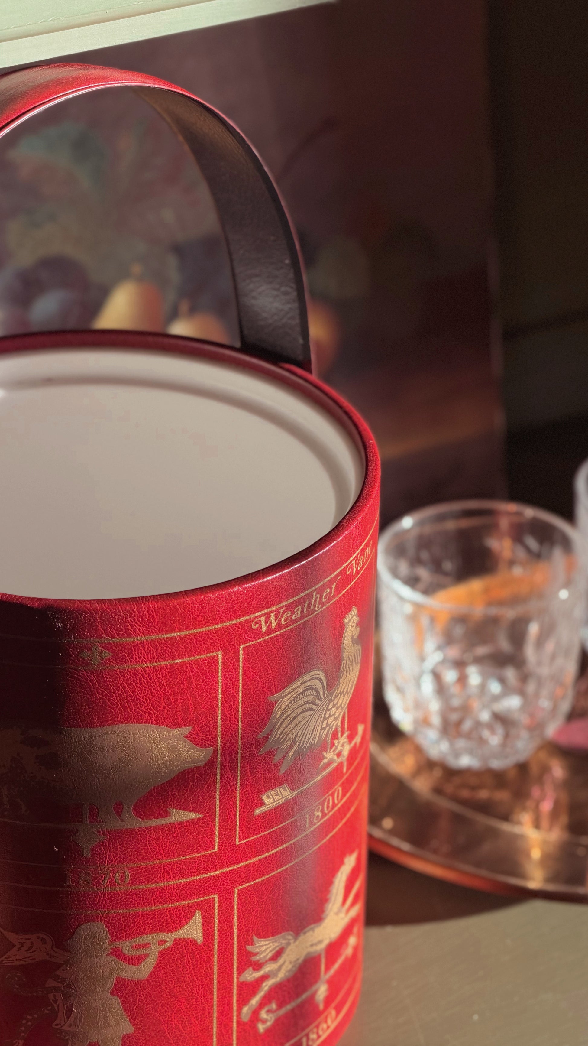 Vintage Georges Briard Weathervane Ice Bucket, shown next to a clear glass on a reflective surface.