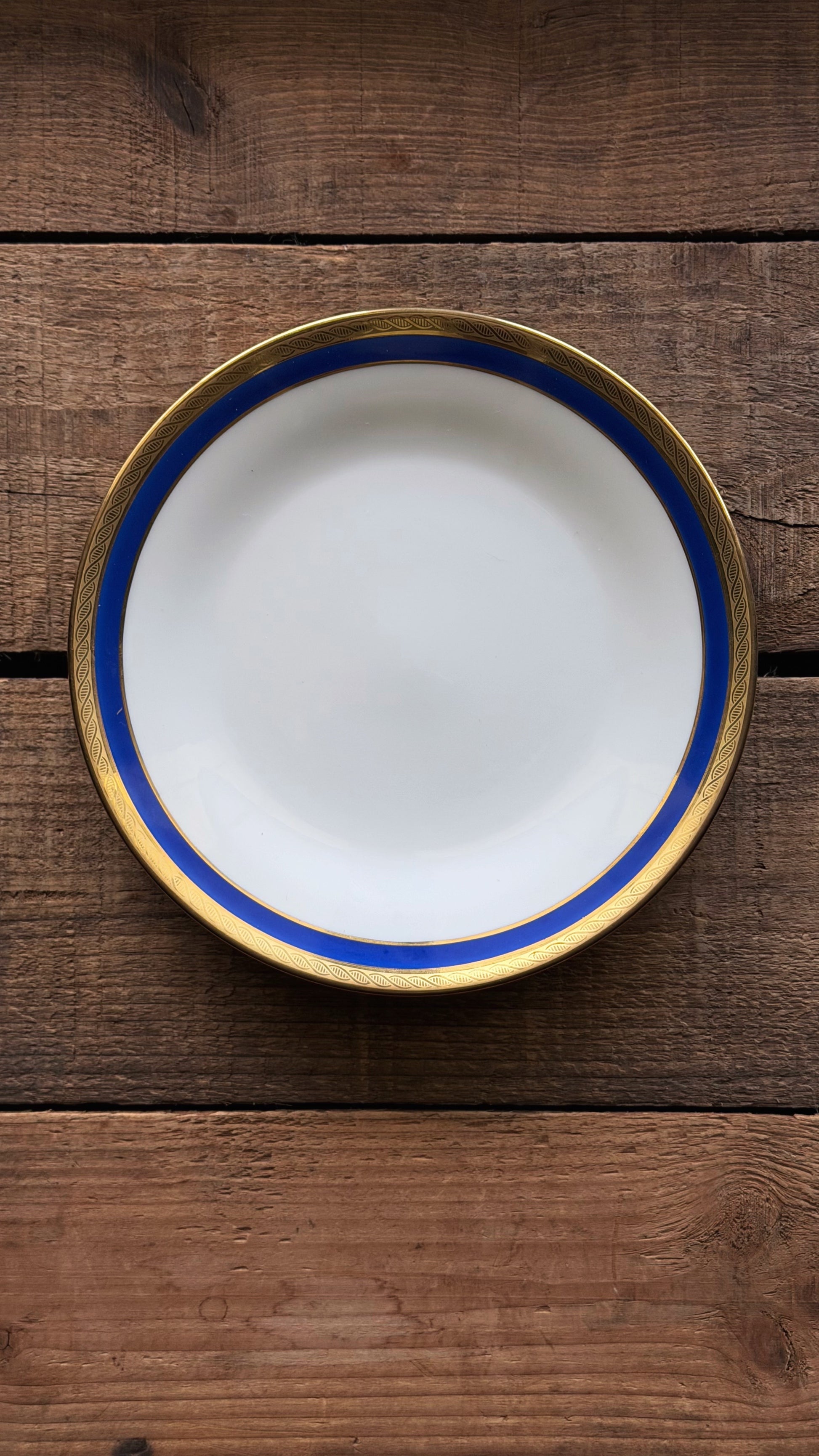 A title: Vintage Richard Ginori Palermo Blue Bread & Butter Plate with a wide blue band and a gold rim, photographed from directly above on a rustic dark wood plank surface.