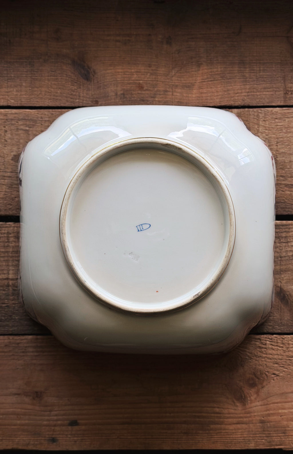 A Vintage Royal Vienna Style Hand Painted Serving Bowl with rounded corners, photographed from directly above on a rustic dark brown wooden surface.