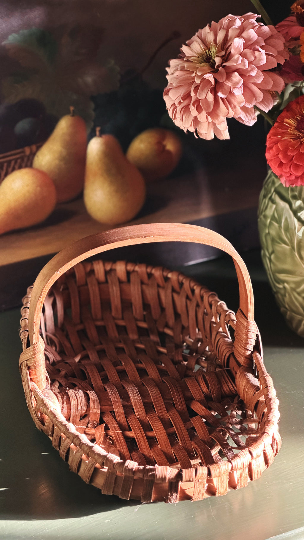 Vintage Woven Single-Handle Tabletop Basket on a green shelf by a vase of fresh flowers