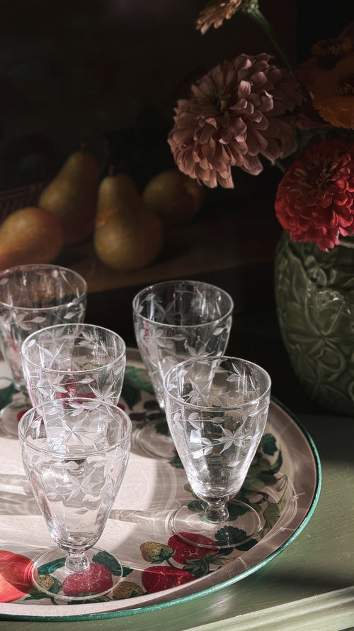 Vintage Etched Crystal Starburst Aperitif | Cordial Glasses arranged on a decorative floral tray, with a dark rustic background featuring pears and flowers.