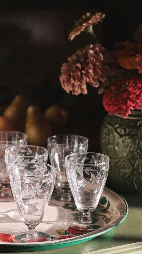 Vintage Etched Crystal Starburst Aperitif | Cordial Glasses arranged on a decorative tray, with a dark floral and fruit background.