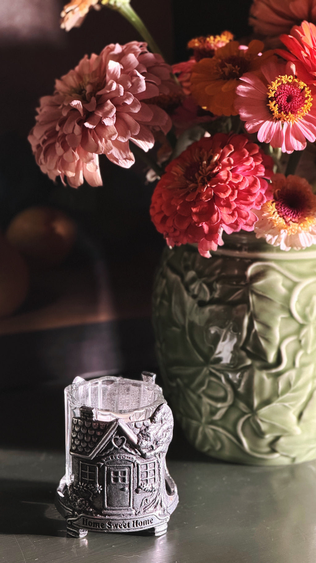 A small silver-toned metal candle holder shaped like a house