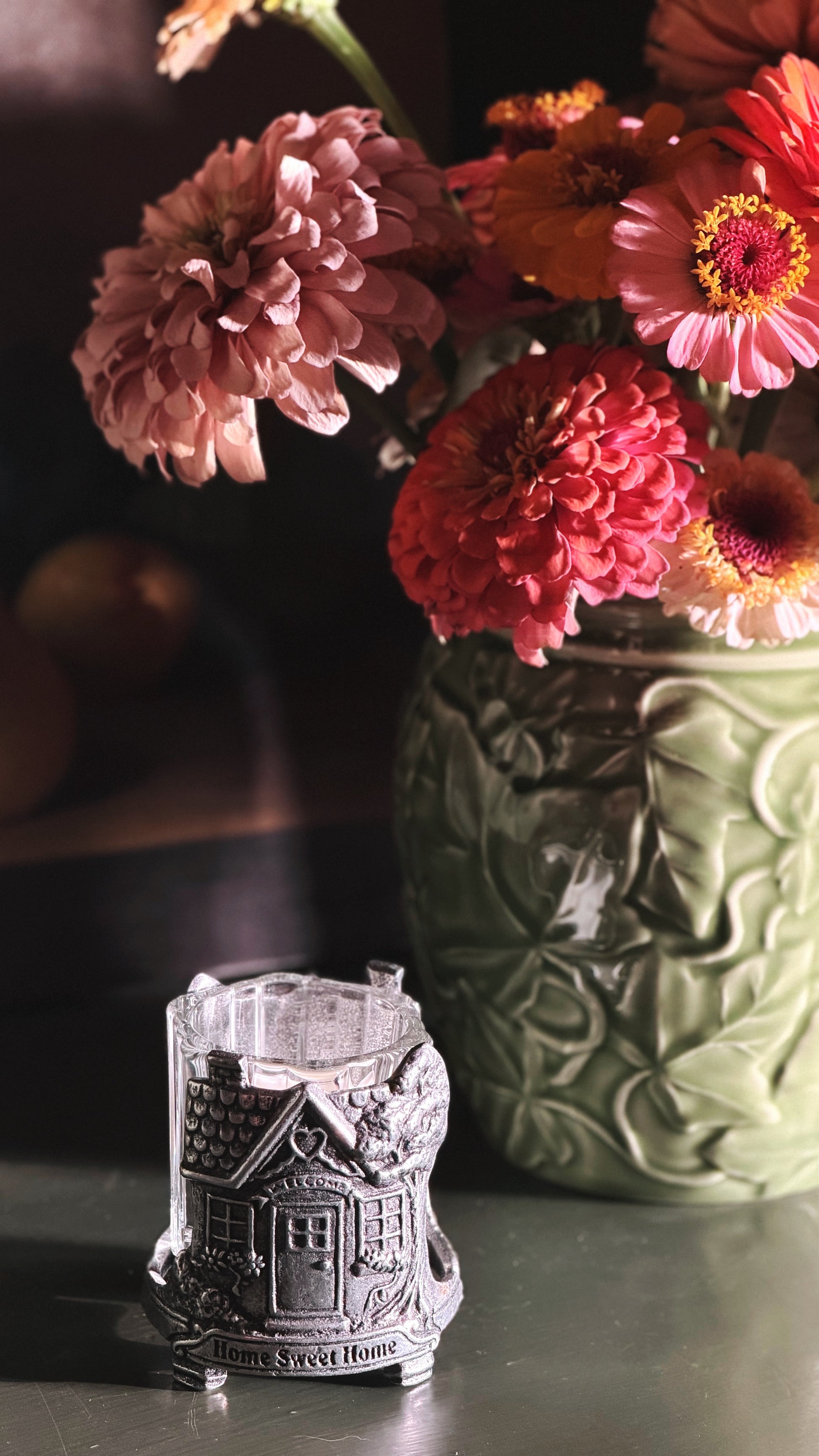 A small silver-toned metal candle holder shaped like a house