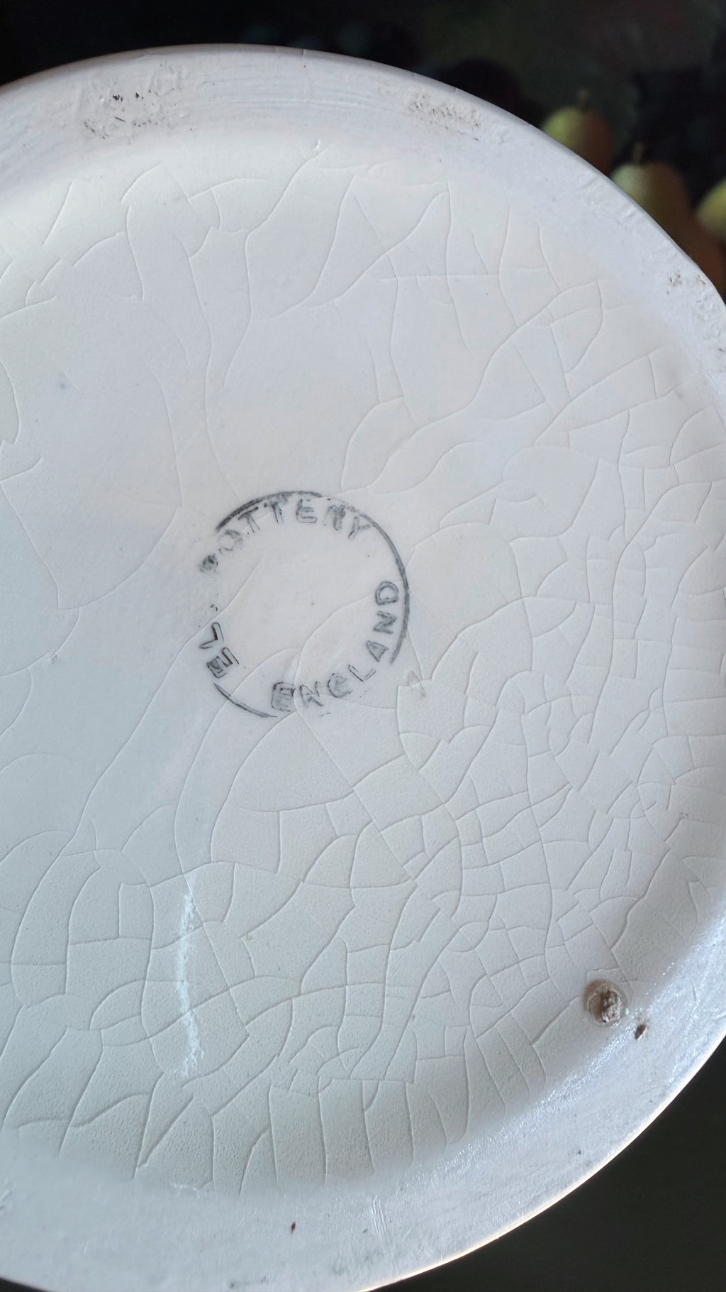 Close-up of the bottom of a white ceramic plate with a crackle glaze pattern and a circular 'Made in England' mark in the center.