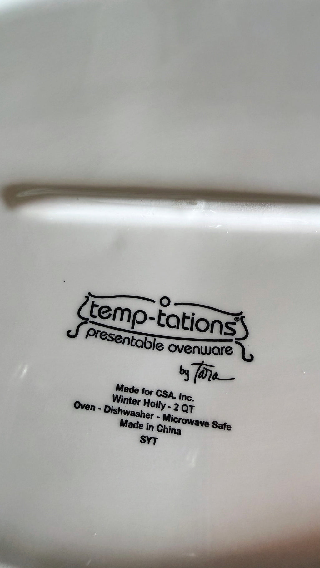 Close-up of the bottom of a white Temp-tations presentable ovenware item, showing printed black text including the Temp-tations logo and product details.
