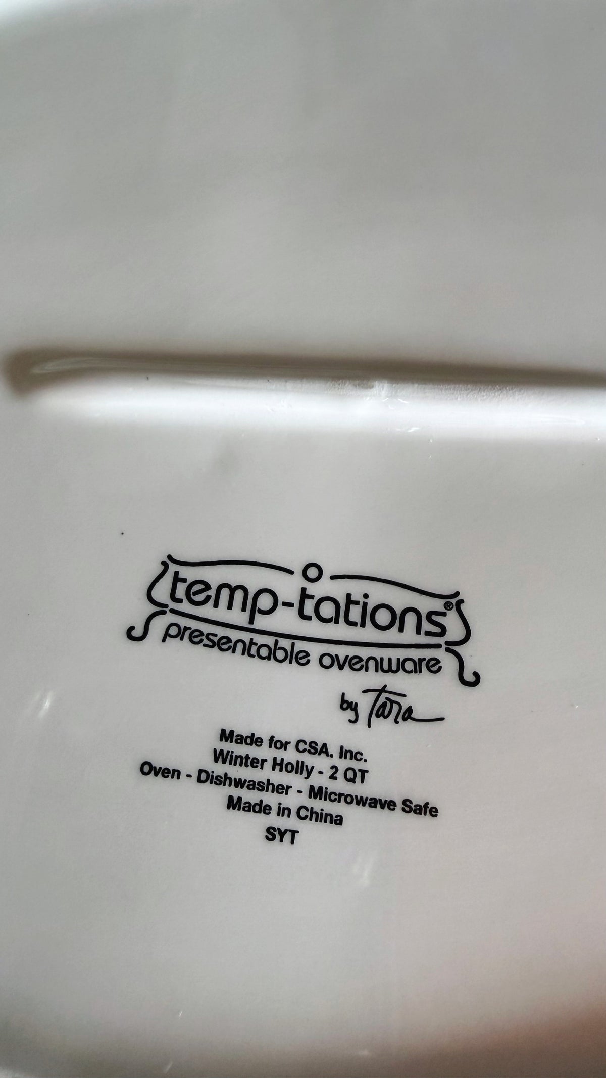 Close-up of the bottom of a white Temp-tations presentable ovenware item, showing printed black text including the Temp-tations logo and product details.