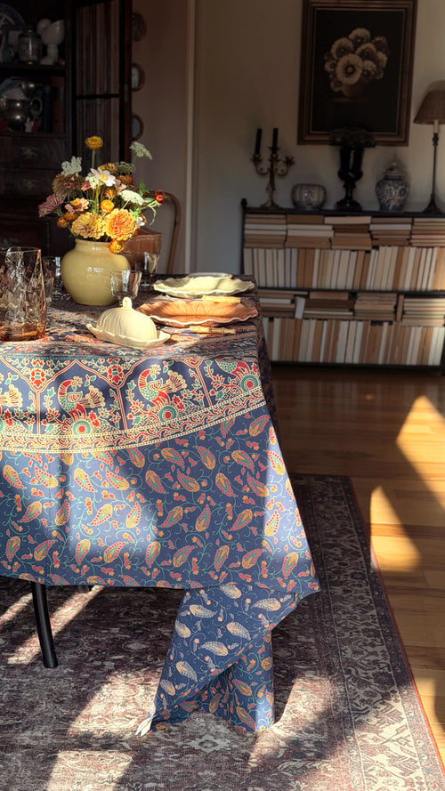 A Vintage Indian Cotton Floral Block Print Tablecloth with a detailed orange, beige, and red botanical pattern draped over a dining table in a sunlit, traditional room.