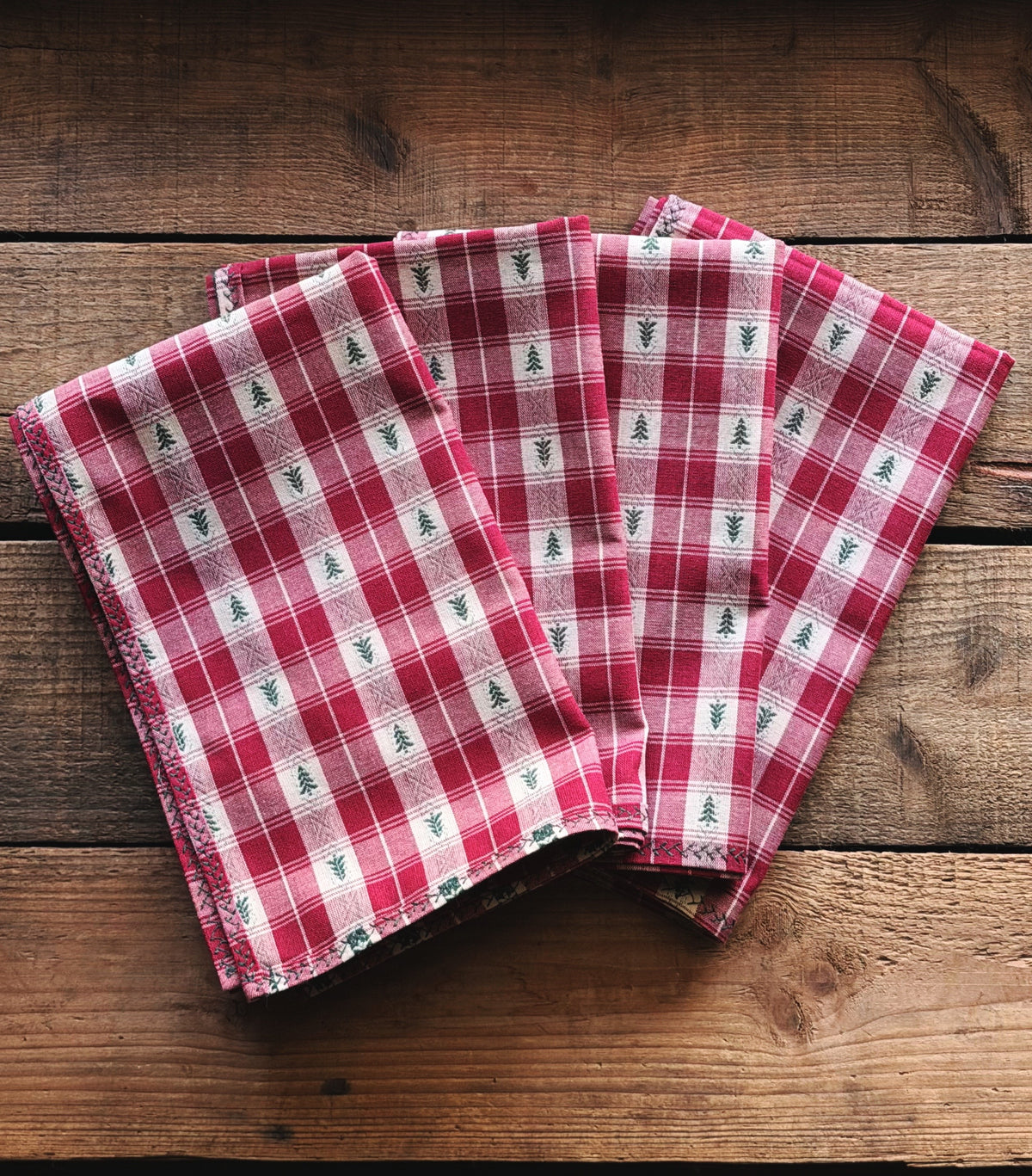 Set of 4 Vintage Red Plaid Christmas Tree Cloth Napkins arranged on a rustic wooden background.