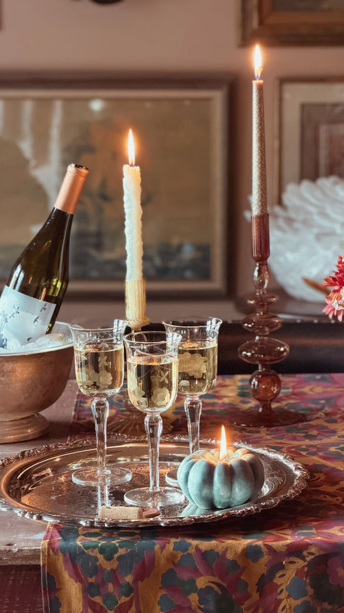 A table set with candles  and wine and a set of Vintage Etched Crystal Tulip Wine Glasses on a silver tray