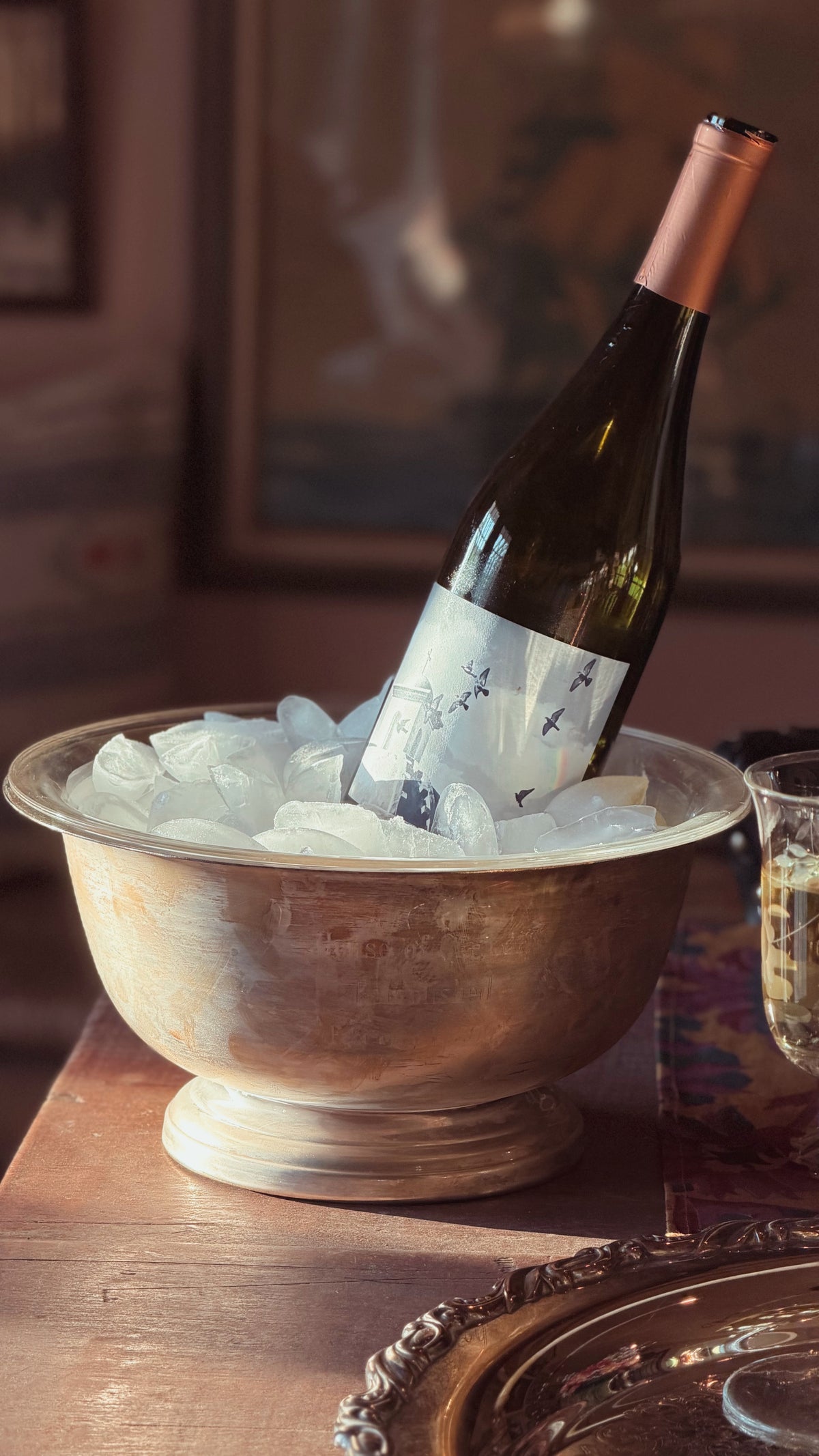 A Vintage Wallace Silver Revere Bowl with Liner filled with ice and a wine bottle.