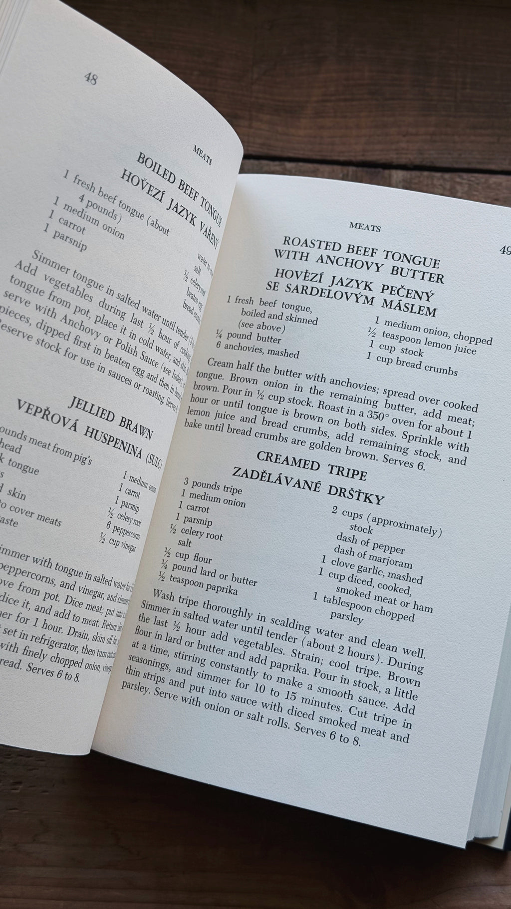 An open cookbook spread showing printed recipes on both pages, photographed from above on a dark wooden surface.