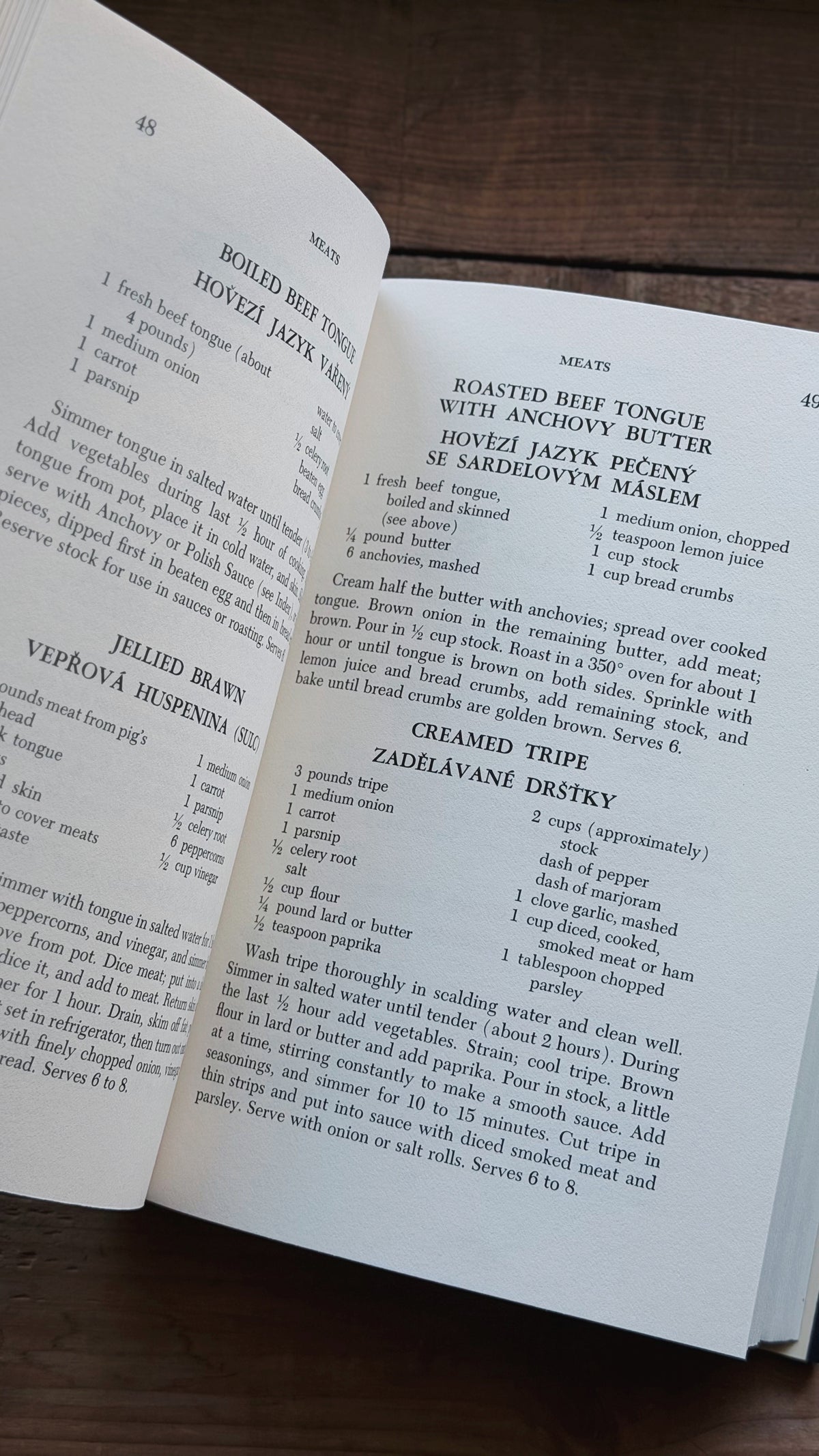 An open cookbook spread showing printed recipes on both pages, photographed from above on a dark wooden surface.
