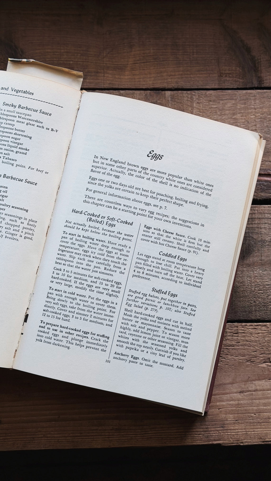An open vintage cookbook or recipe book showing printed egg preparation pages, placed on a rustic dark wooden surface.