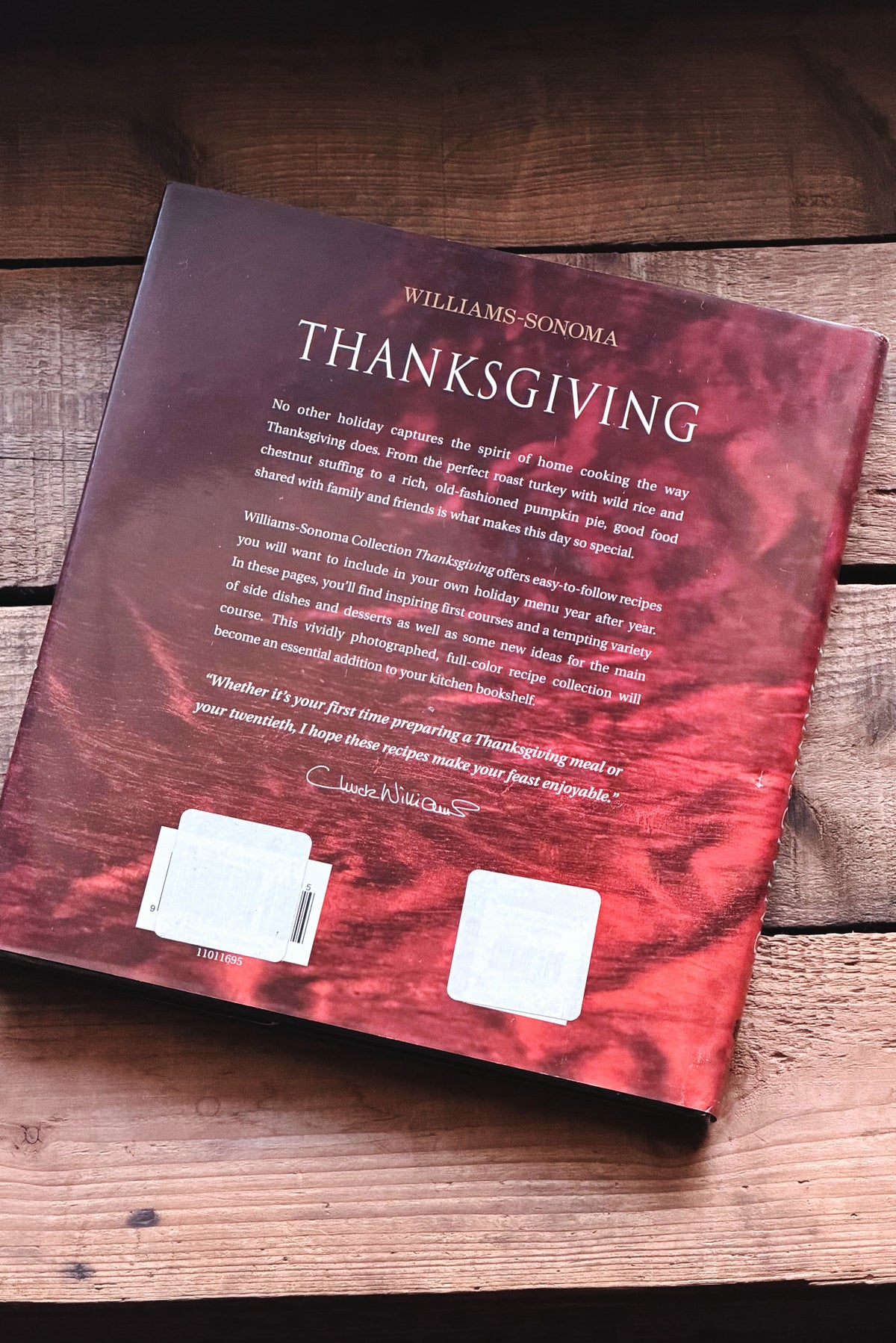 The back cover of the book 'Thanksgiving' by Williams Sonoma, featuring a red and black marbled pattern, photographed on a rustic wooden surface.