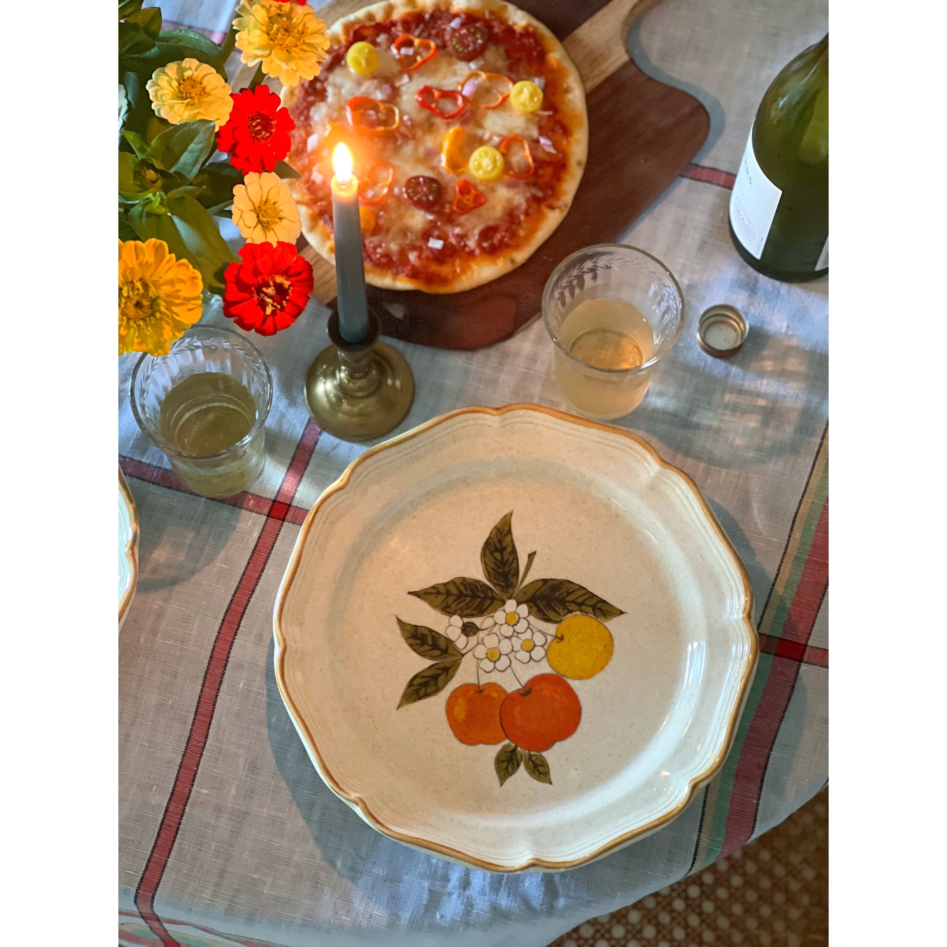 vintage fruit pattern dinner plate on a table with wine and pizza