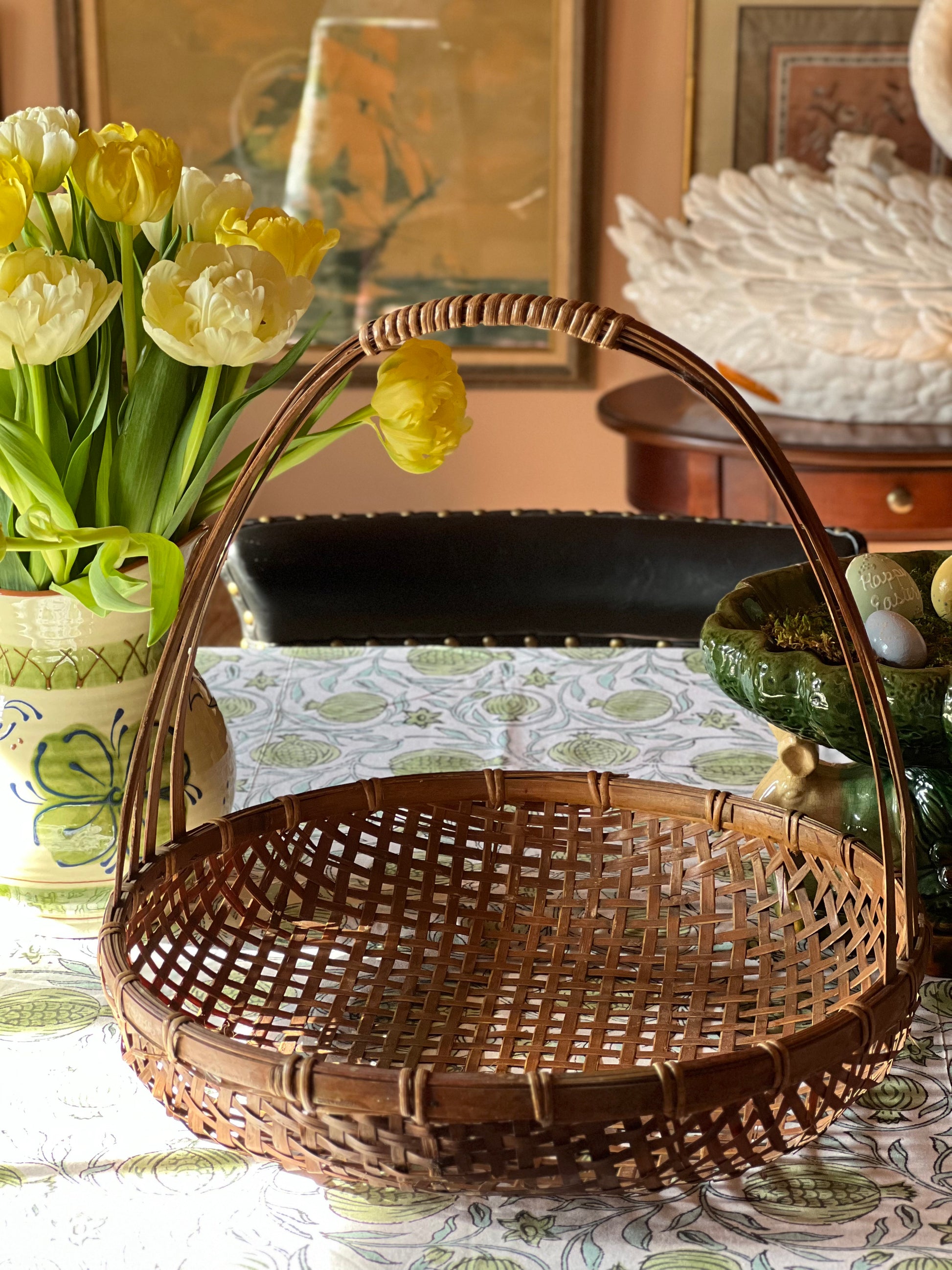 Woven basket on a table with yellow tulips and decorative items in the background