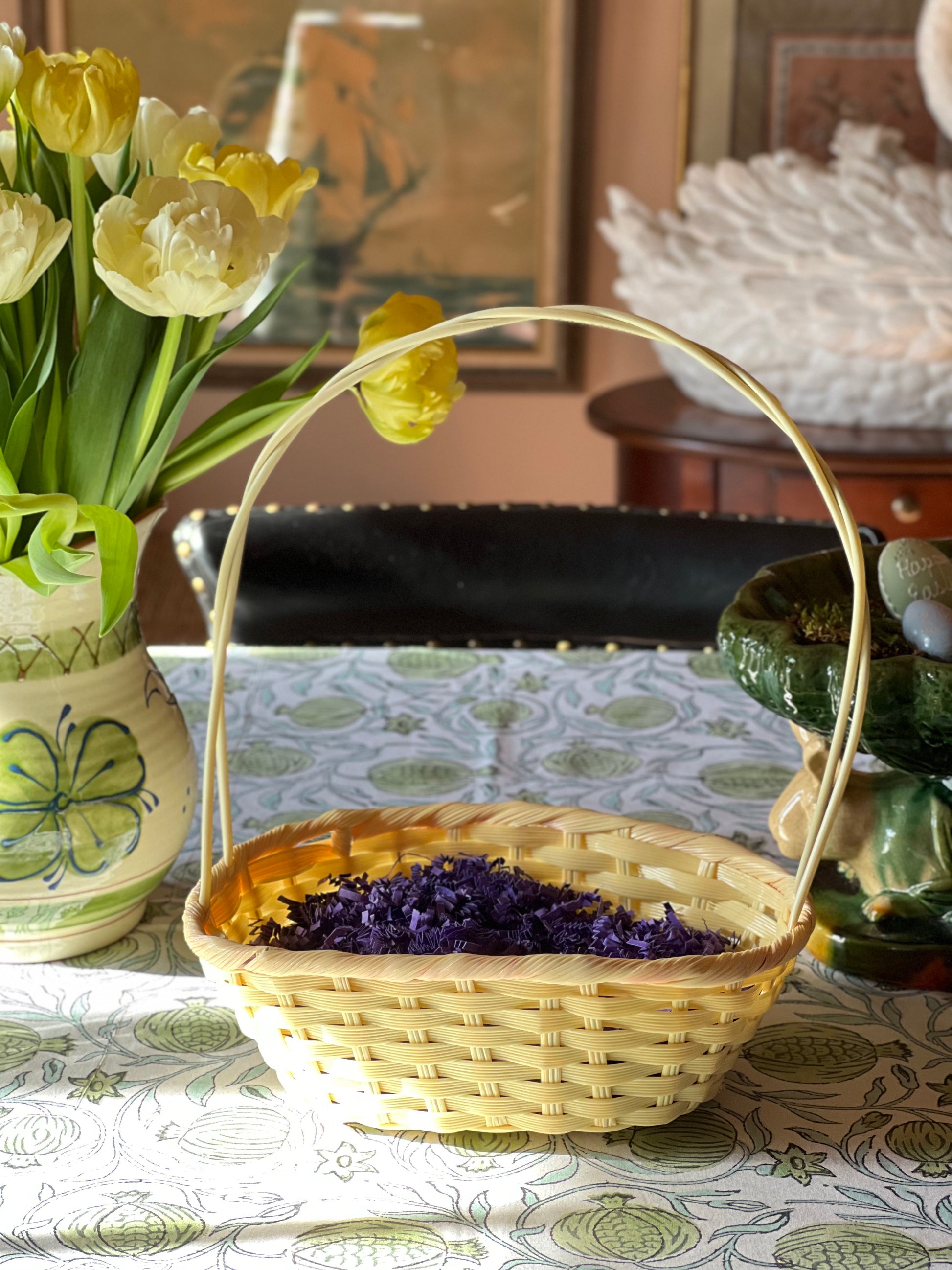 Wicker basket with dried lavender on a table with flowers and decorative items.