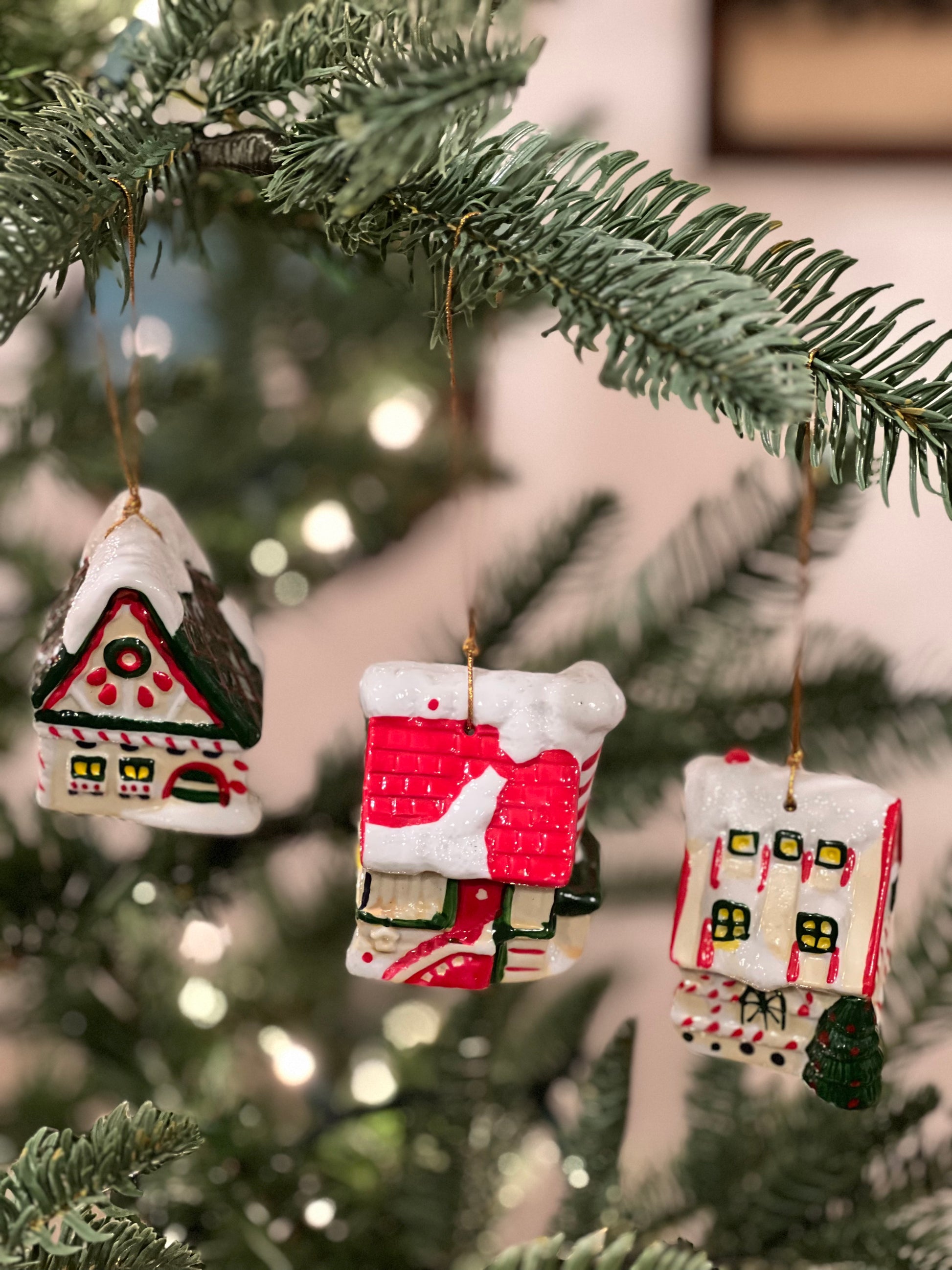 Three small house-shaped Christmas ornaments on a tree