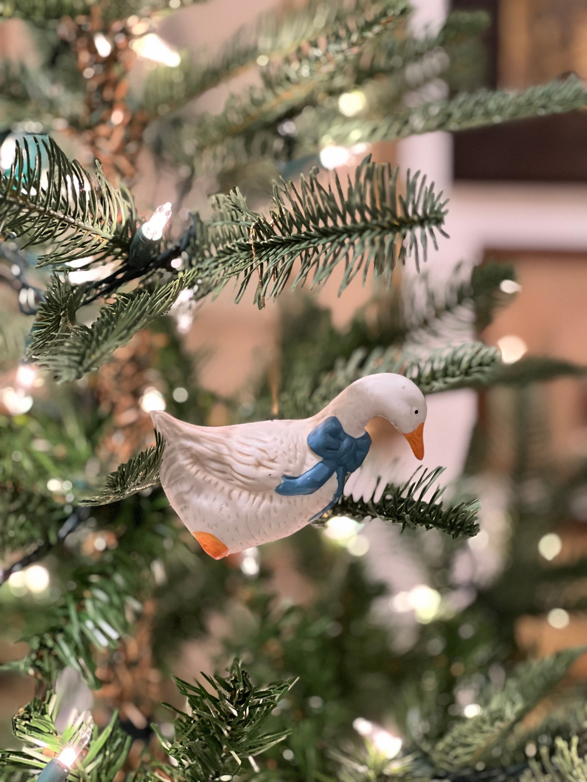 Decorative goose ornament on a Christmas tree with blurred lights in the background