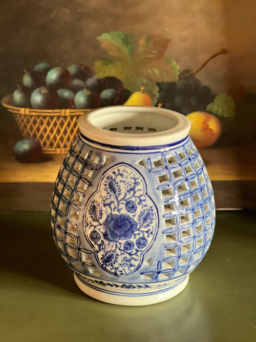 Blue and white ceramic warmer with decorative patterns on a table with fruits in the background