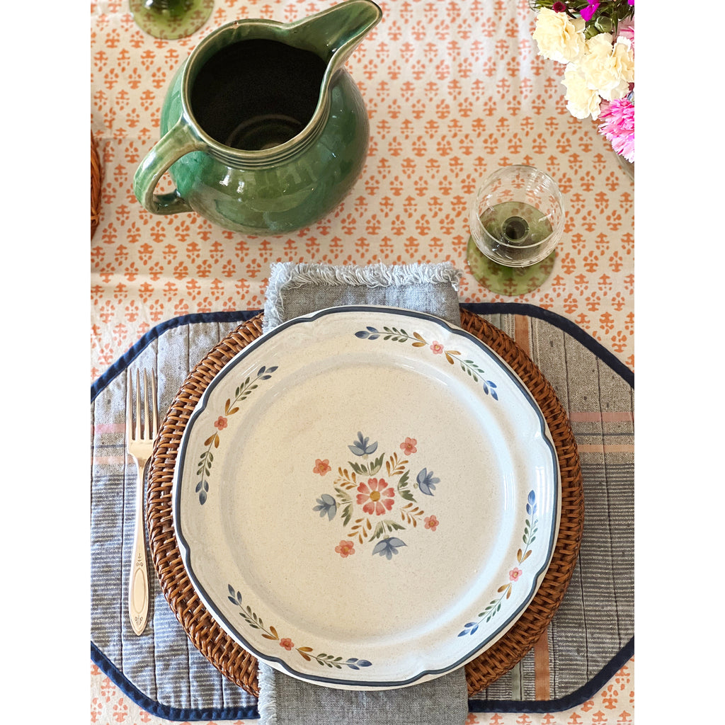 Decorative plate with floral design on a table setting with a pitcher and glass.